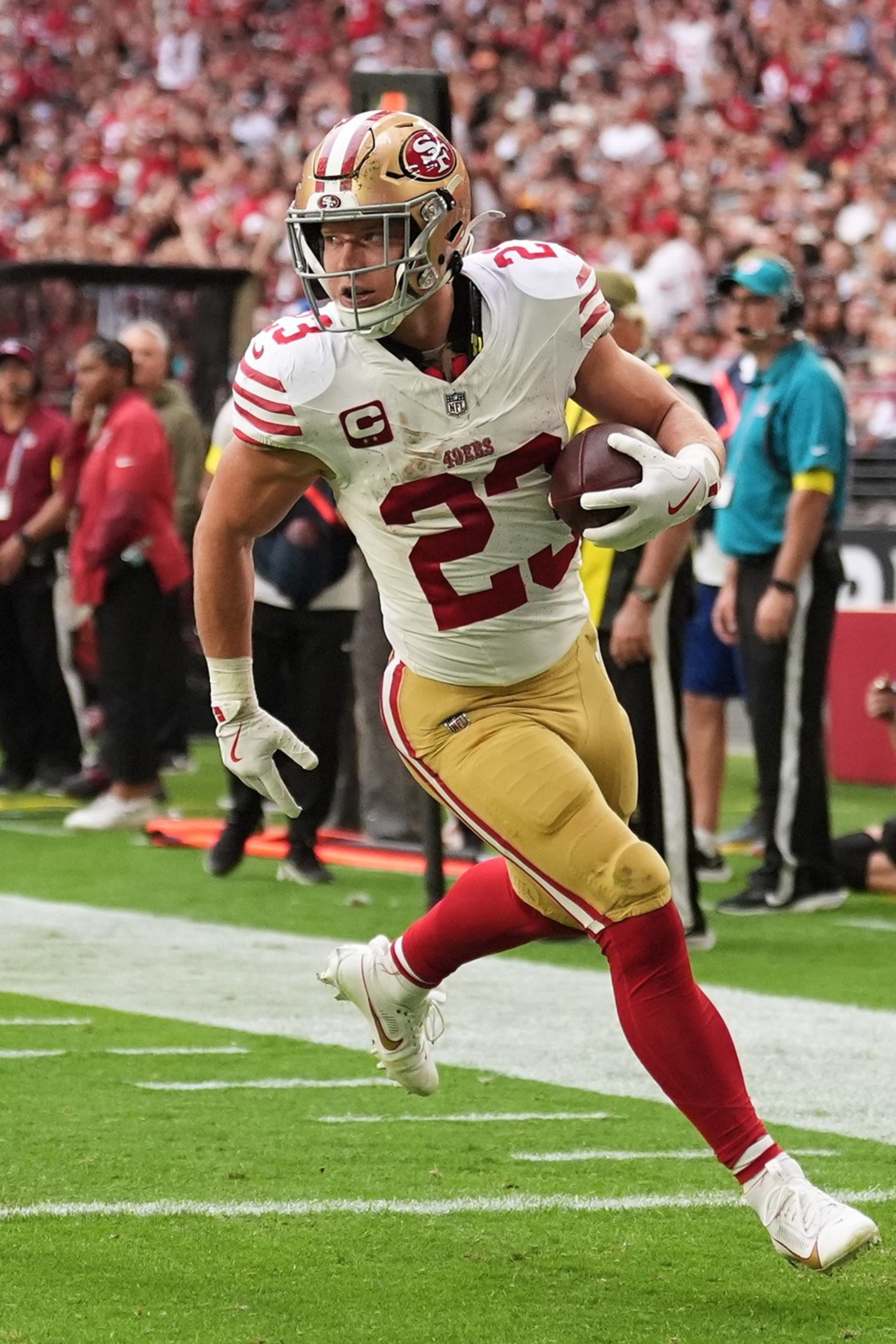 A football player wearing a San Francisco 49ers uniform runs near the end zone with the ball in hand during a game.