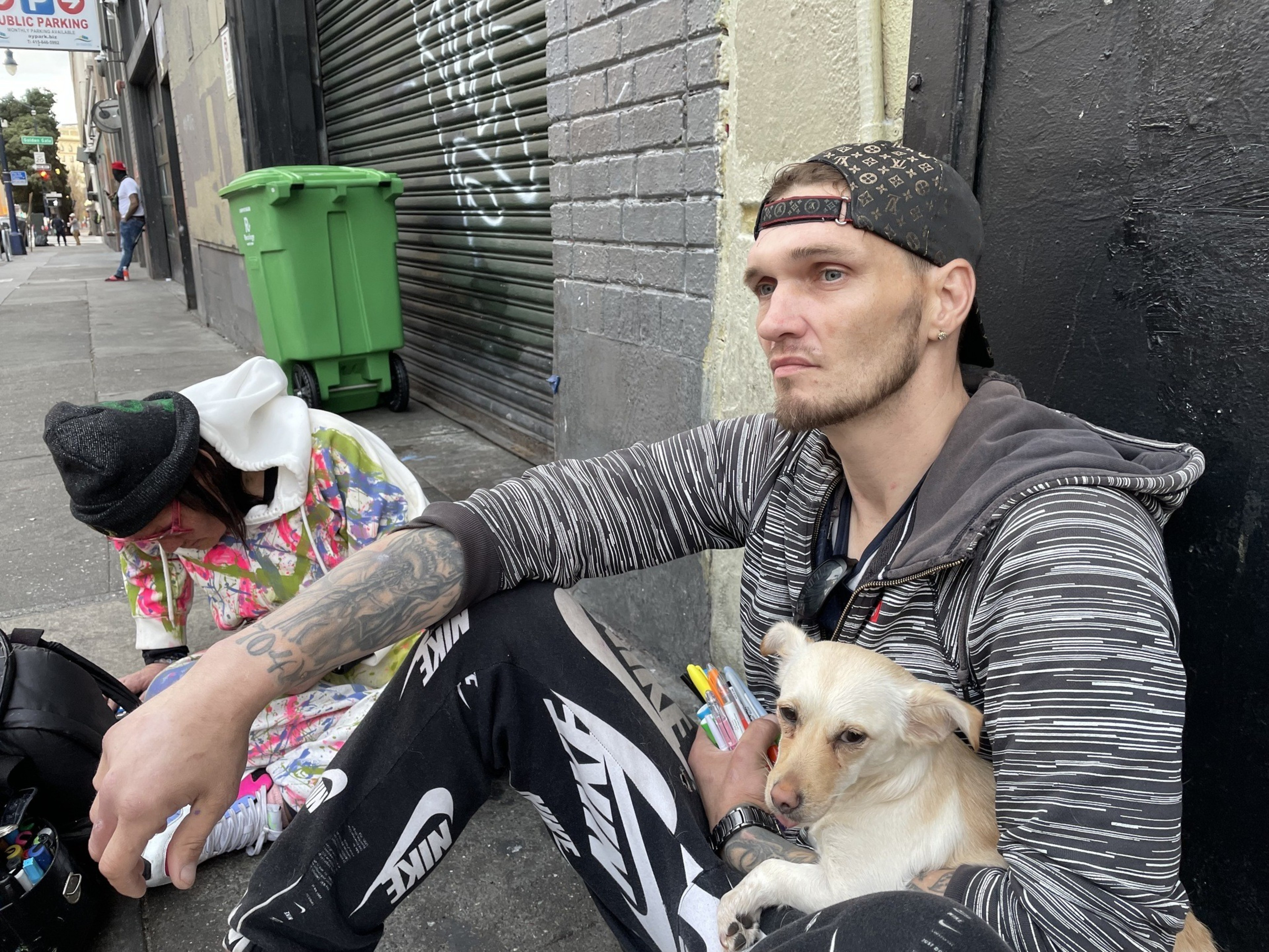 A man sits on the sidewalk.