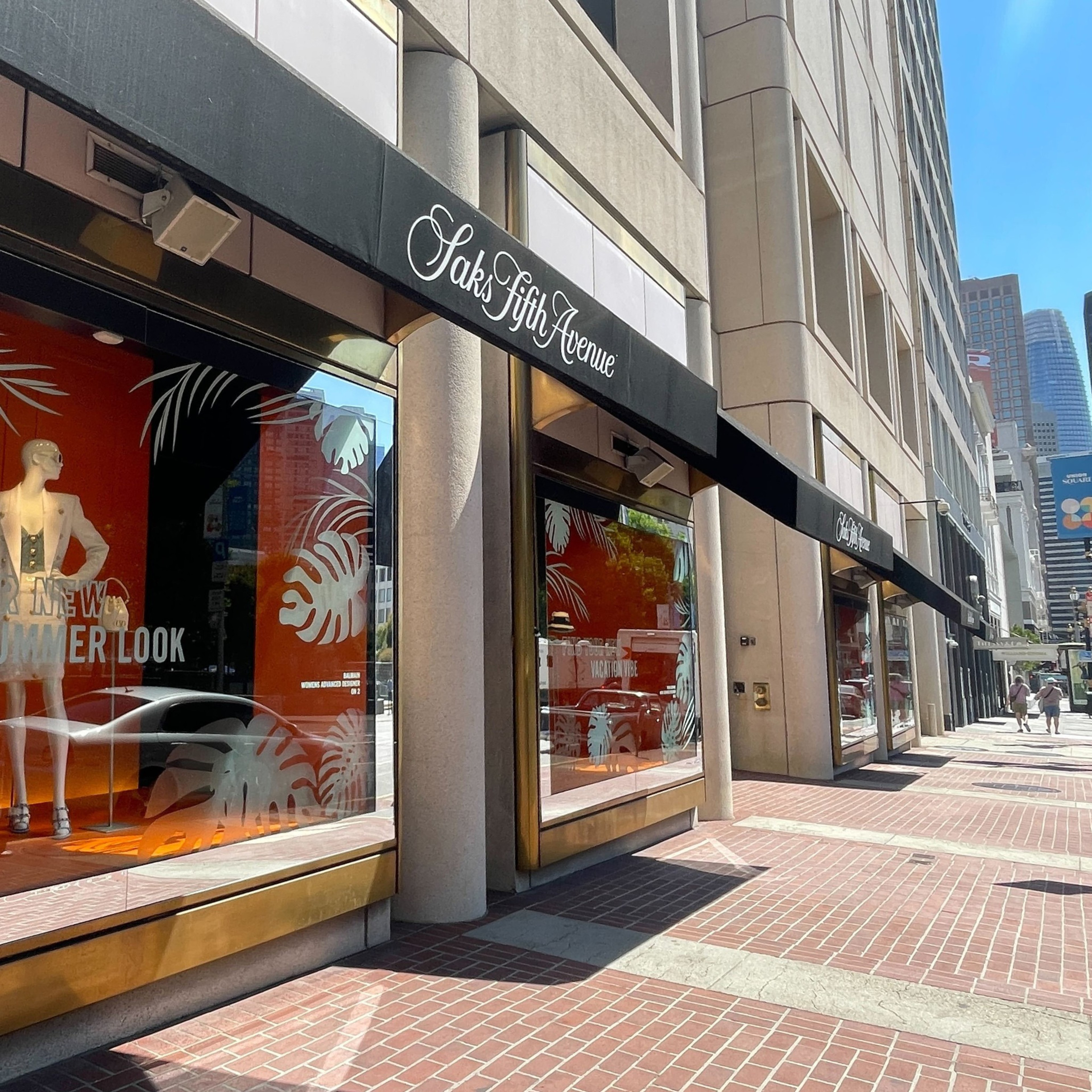 The sun shines on the awnings of a store with a mannequin in the window.