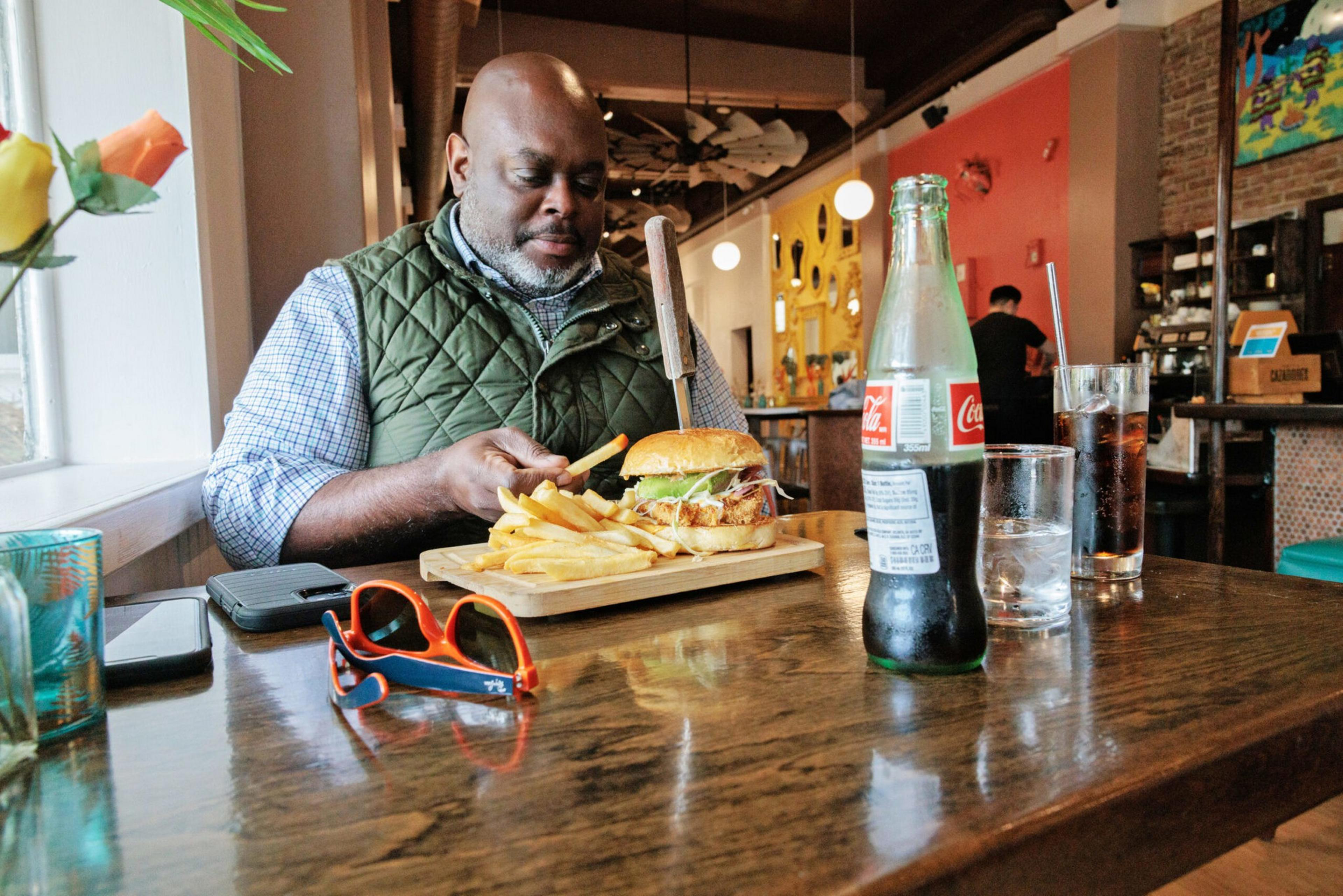 A man sits at a table with his lunch in a restaurant.