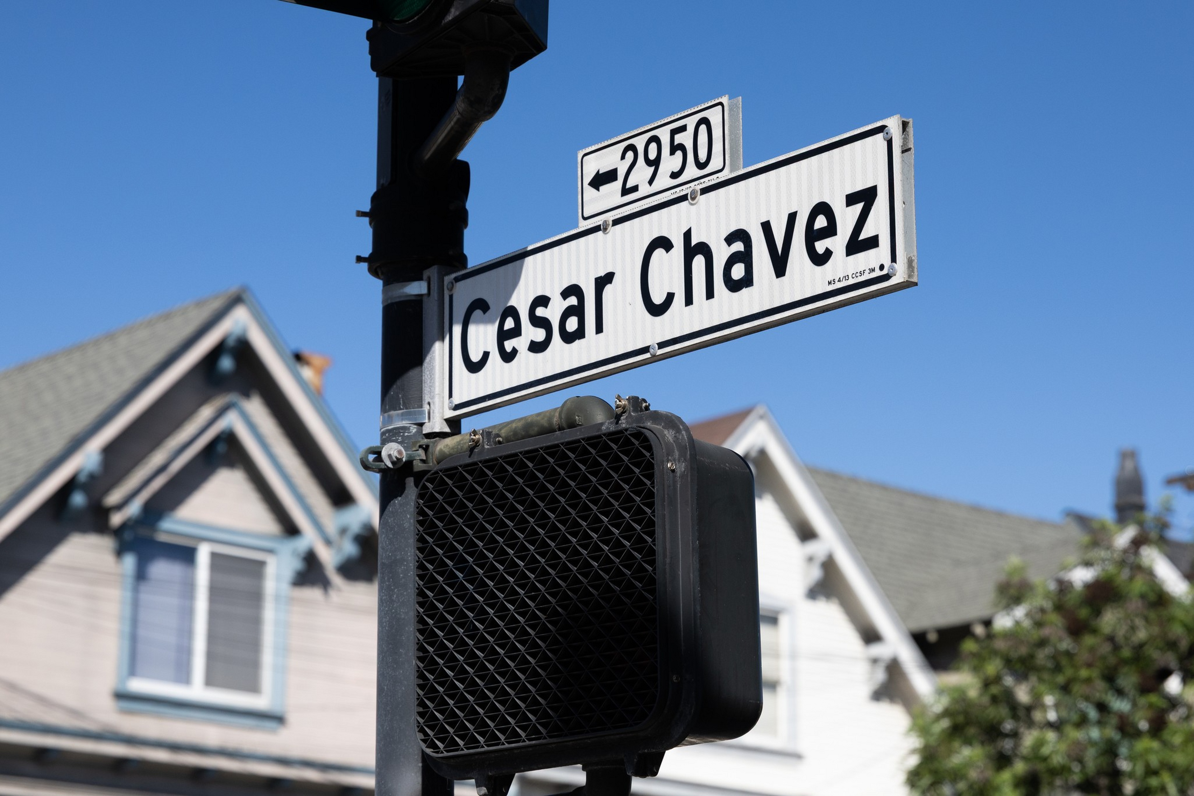 A black streetlight pole holds a Cesar Chavez street sign with the ...