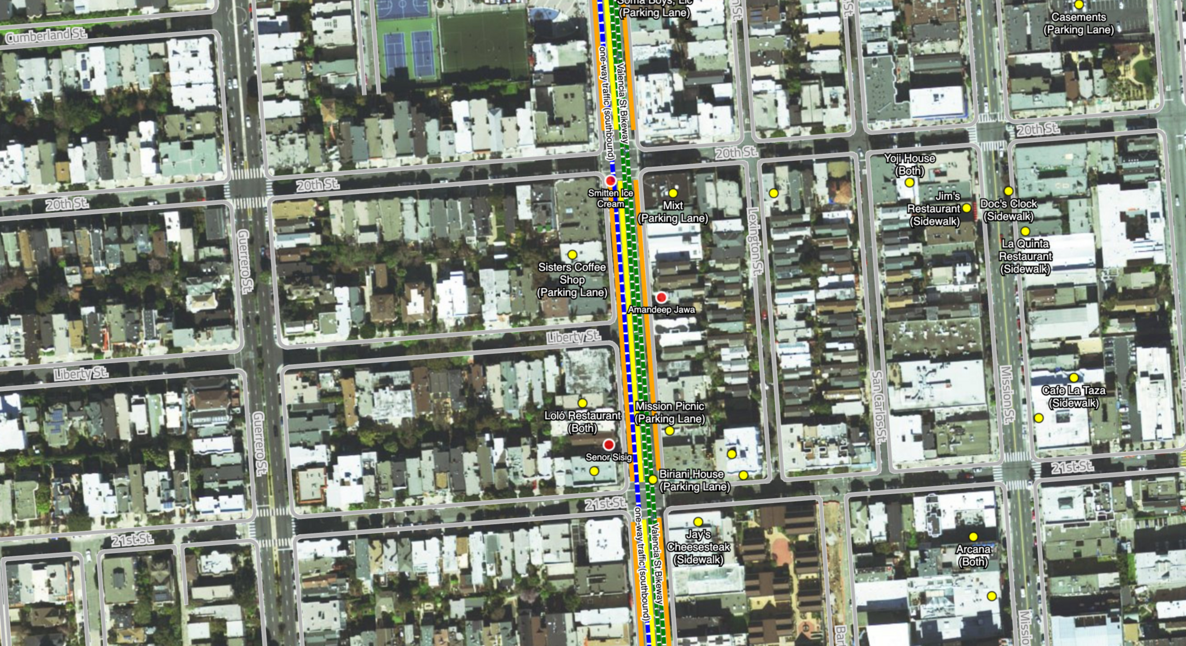 Aerial view of a city grid with marked streets, businesses like coffee shops, restaurants, parking lanes, and a highlighted route with traffic signals.