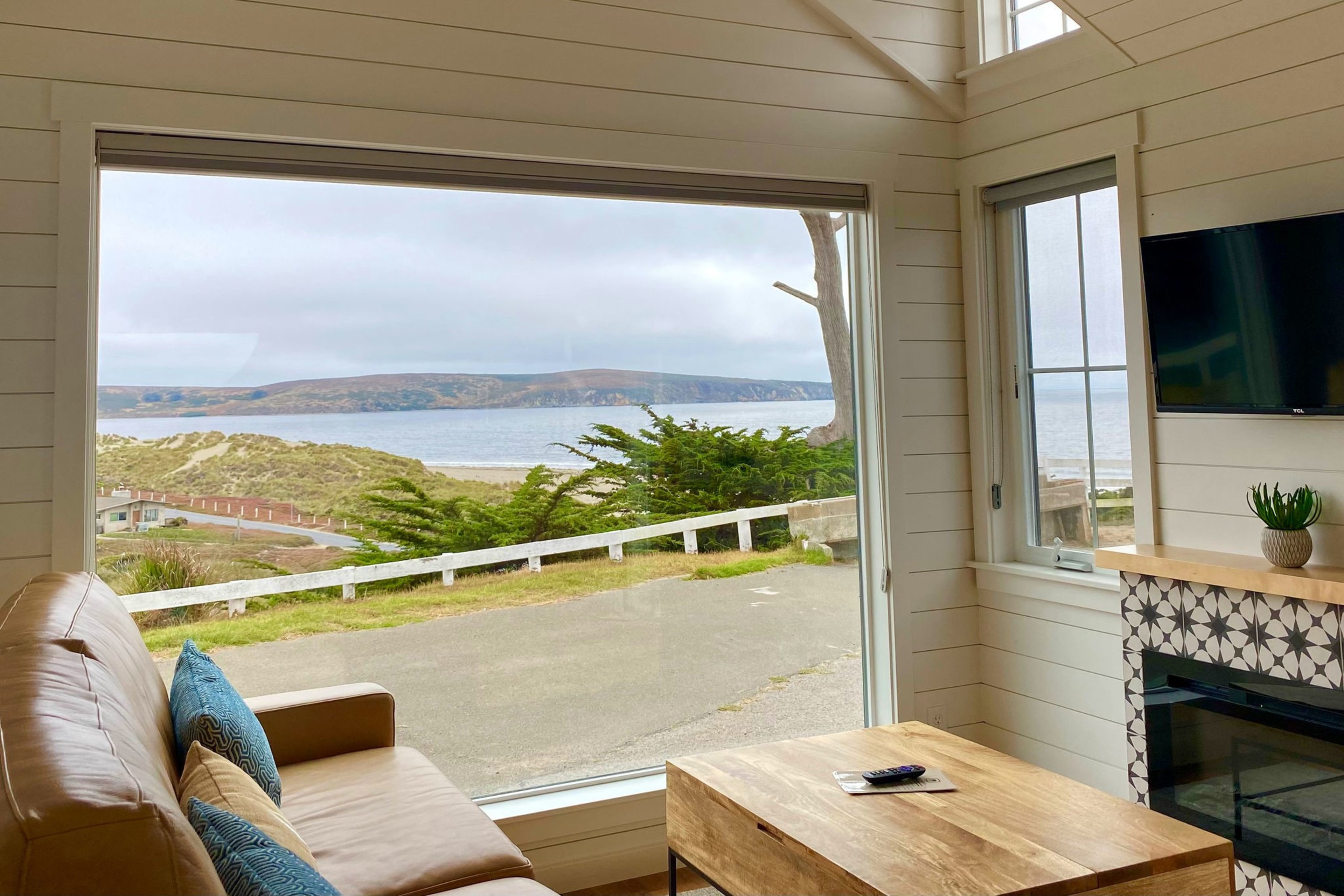 A room with a large window looking out at green bluffs and the ocean