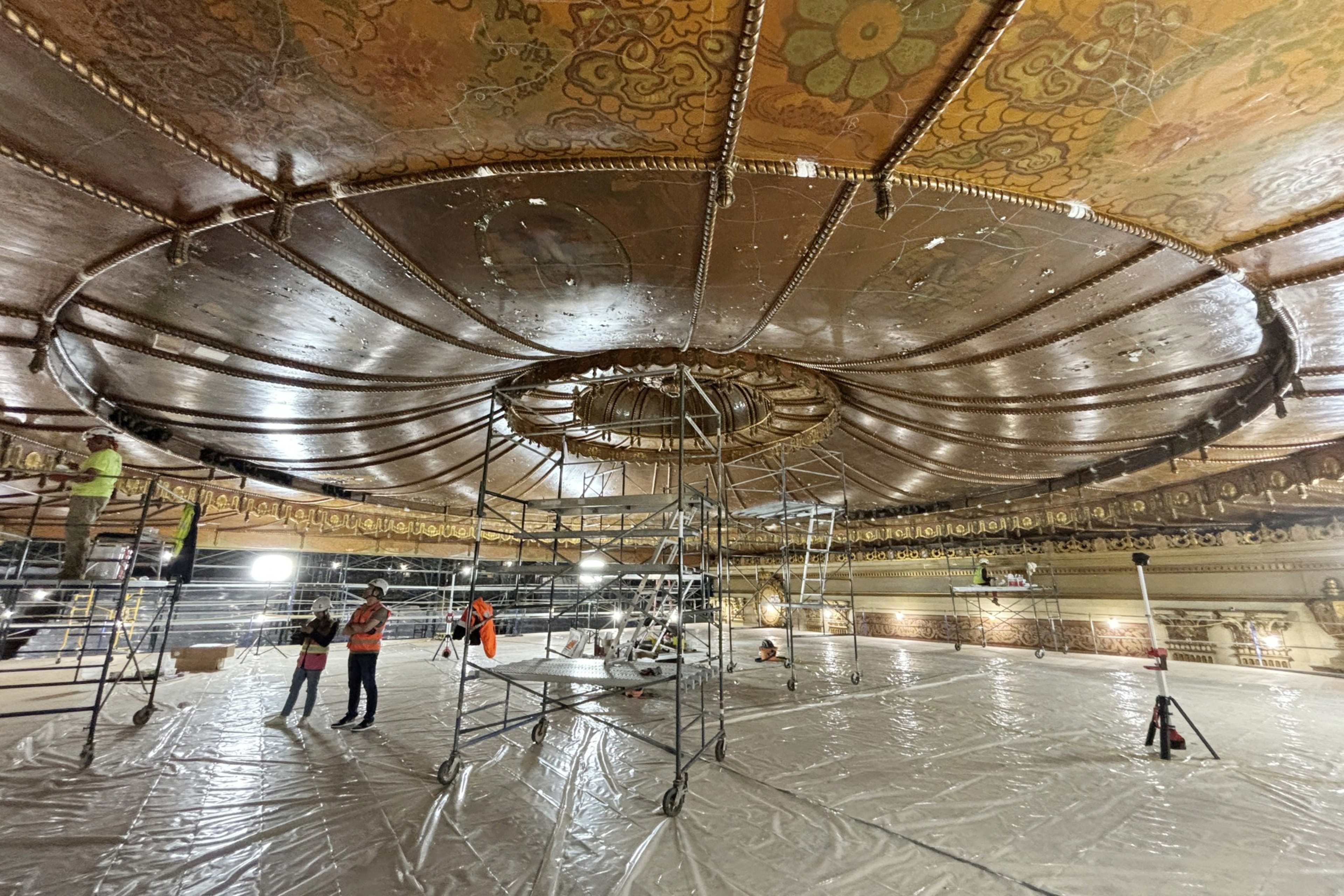 a zoomed-out image of a platform in the Castro Theater showing people at work and the ceiling where the chandelier will go once it's restored.