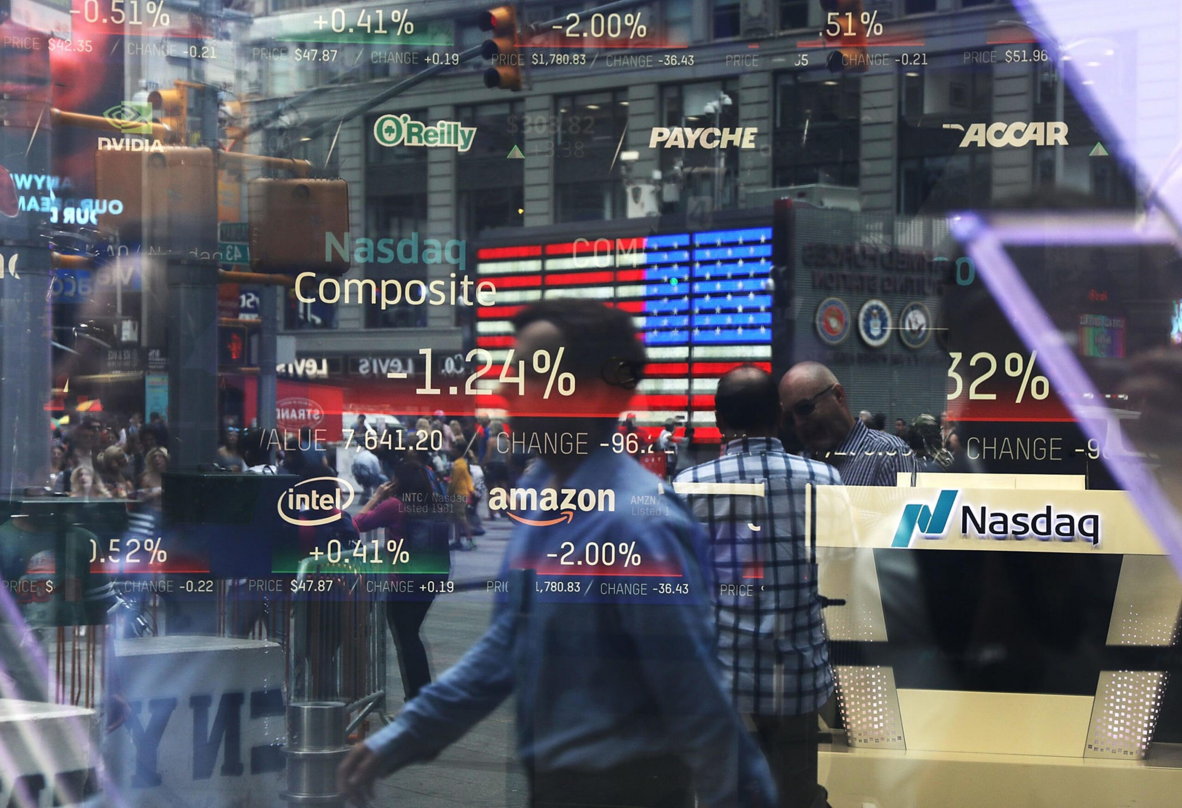 Reflections of people and city buildings blend with Nasdaq stock market ticker symbols and percentage changes on a transparent screen.