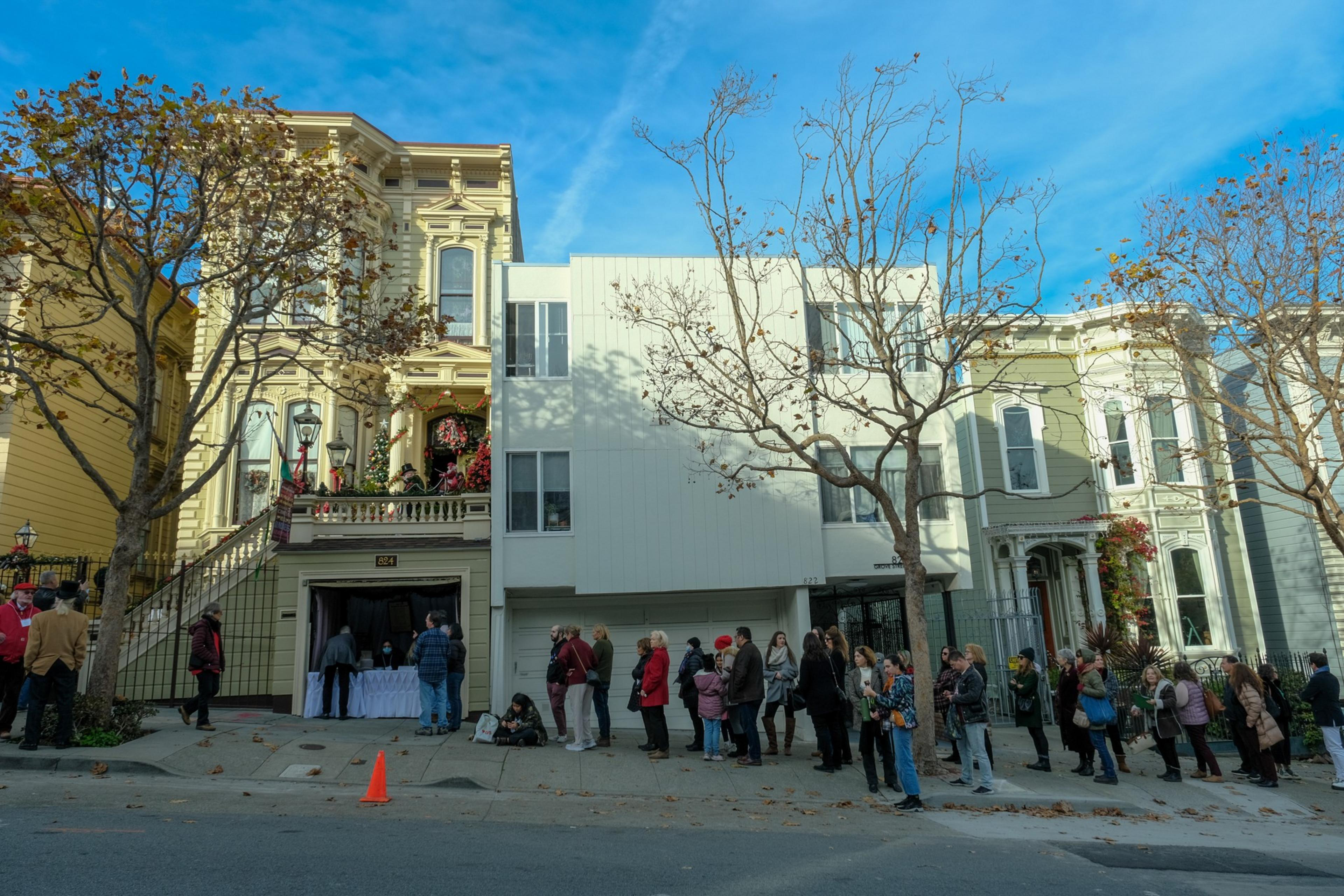 People stand in line outside on a city block where there is an open garage.