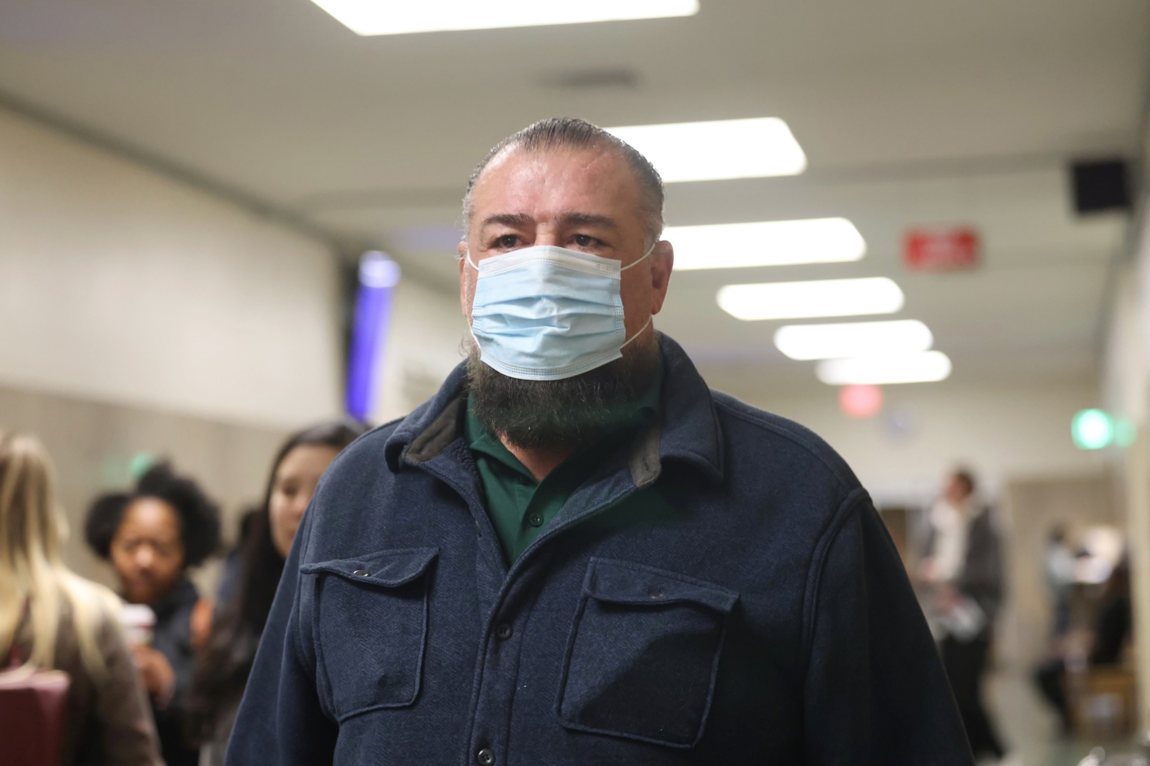 Fomer SFFD Commissioner Don Carmignani, wearing a face mask, walks through the hallways of the Hall of Justice in San Francisco.
