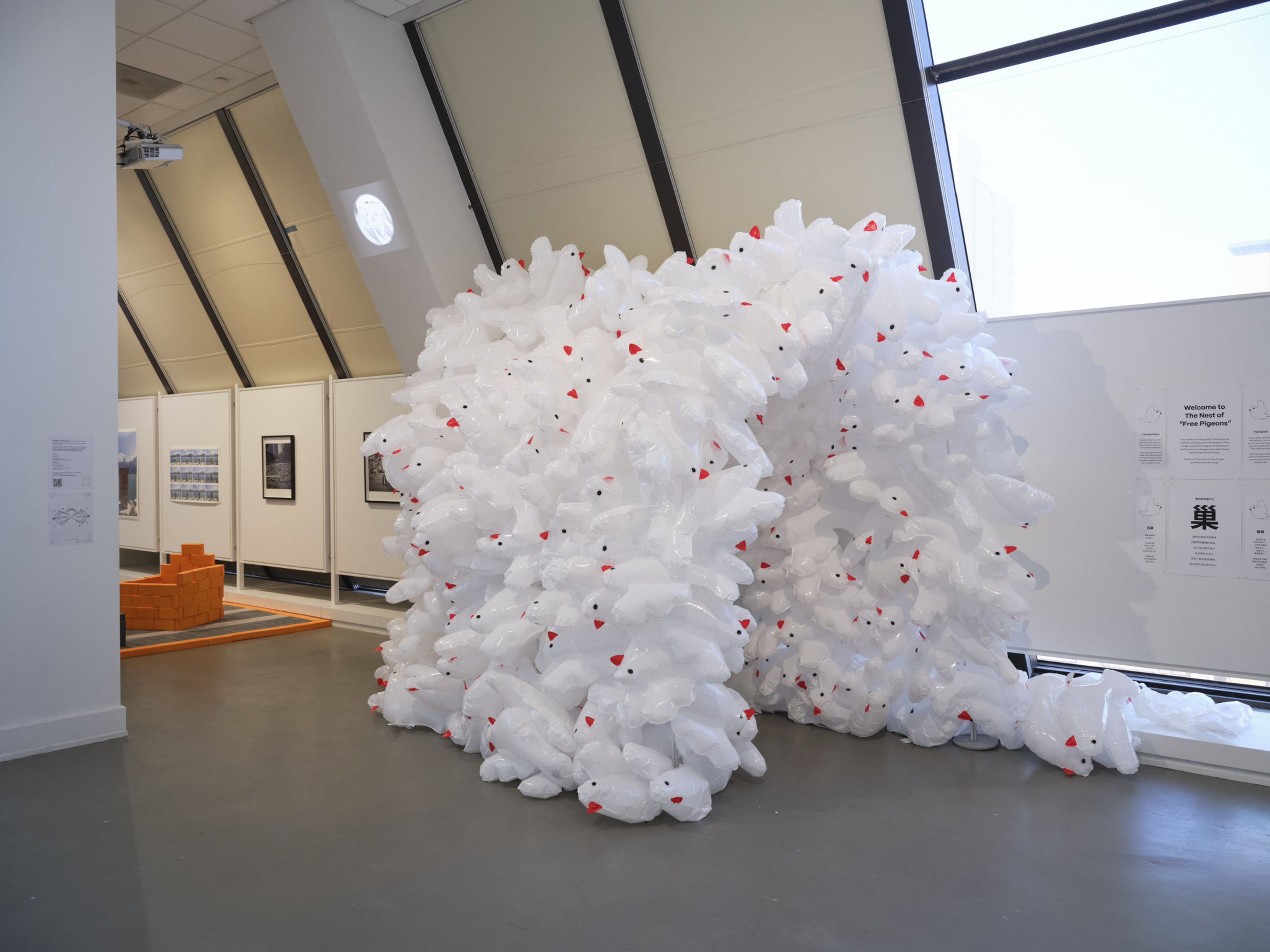 A mass of inflatable pigeons forms an archway in an art gallery's exhibition space.