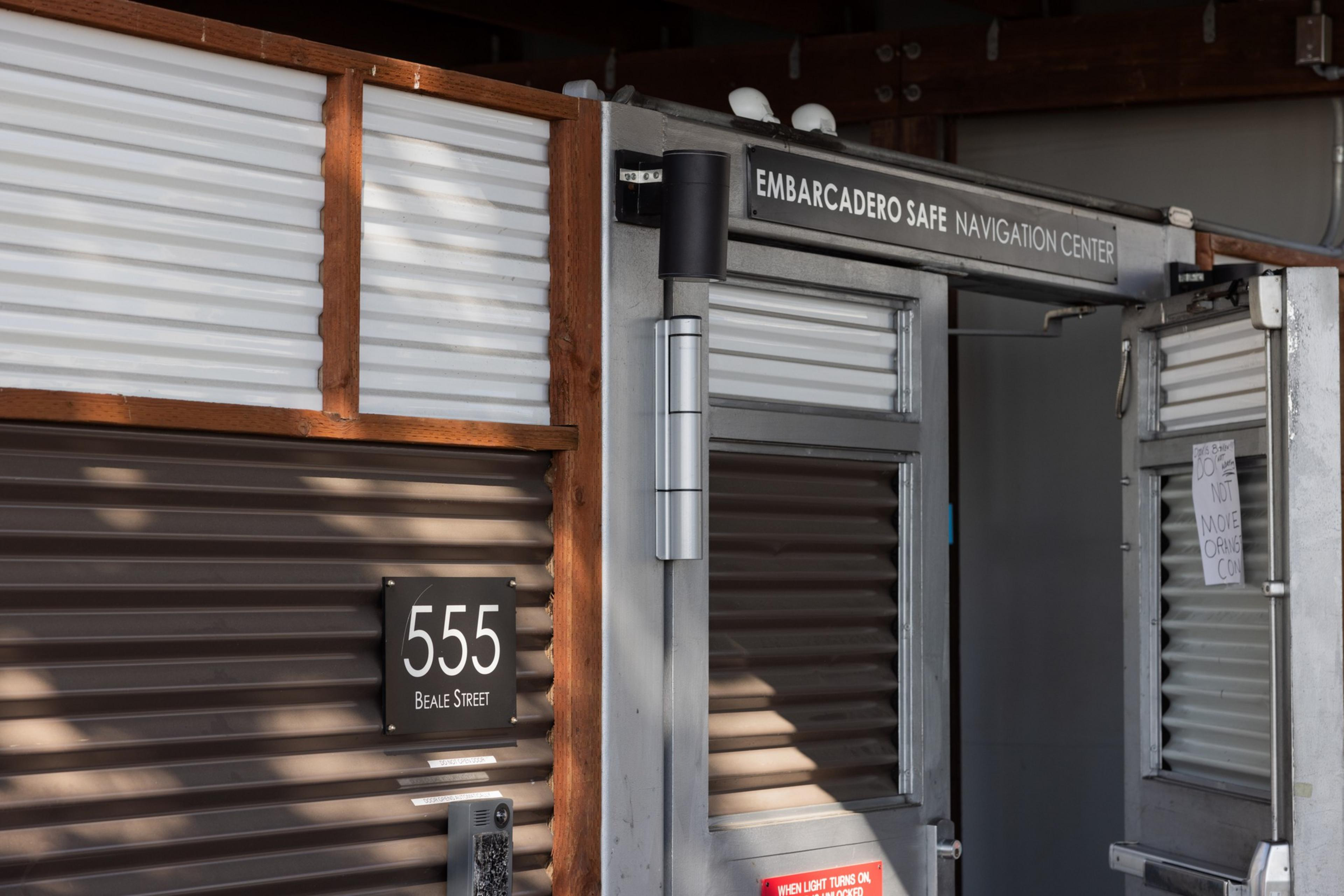 A building entrance labeled "Embarcadero Safe Navigation Center" with an address sign "555 Beale Street" and a partially open door.