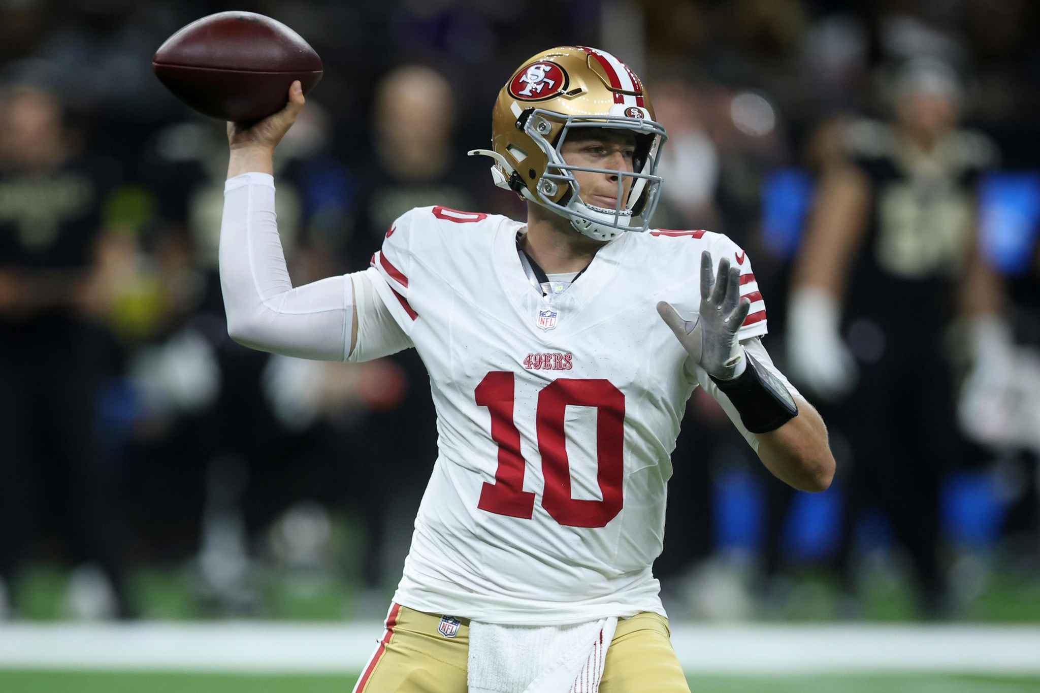 A football player wearing a white San Francisco 49ers jersey with number 10 is preparing to throw a pass during a game.