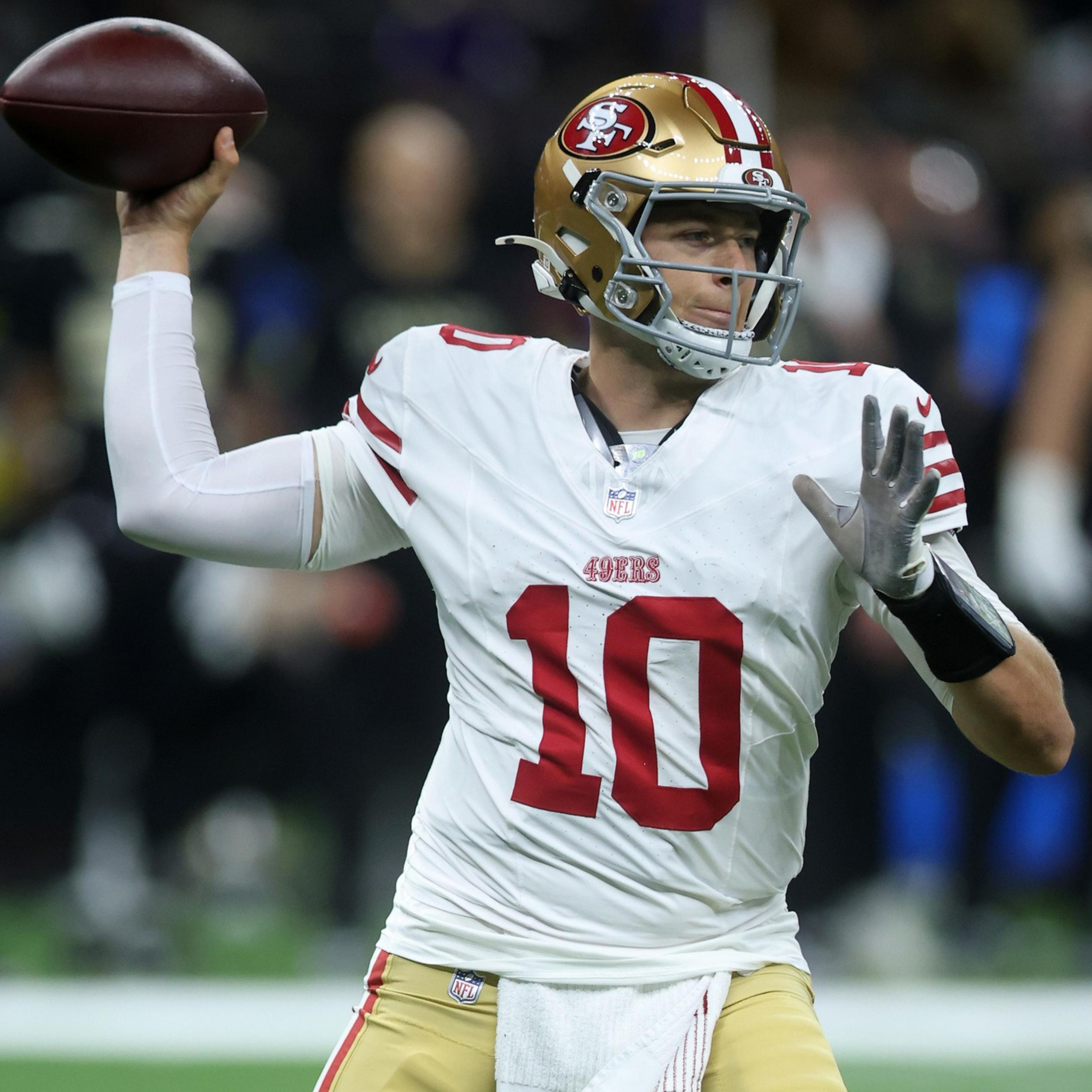 A football player wearing a white San Francisco 49ers jersey with number 10 is preparing to throw a pass during a game.