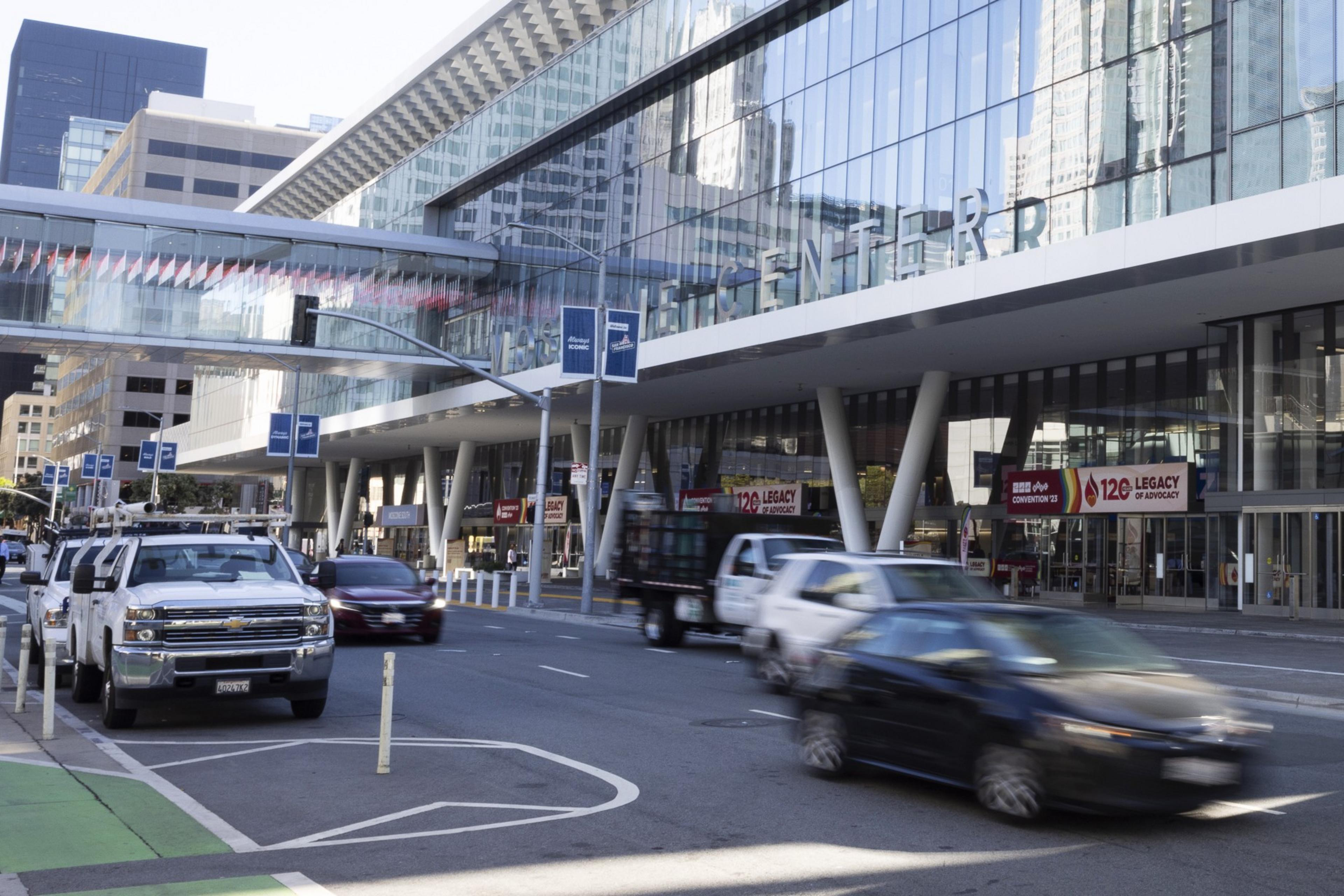 Several cars pass down Howard Street quickly with Moscone Center in the background.