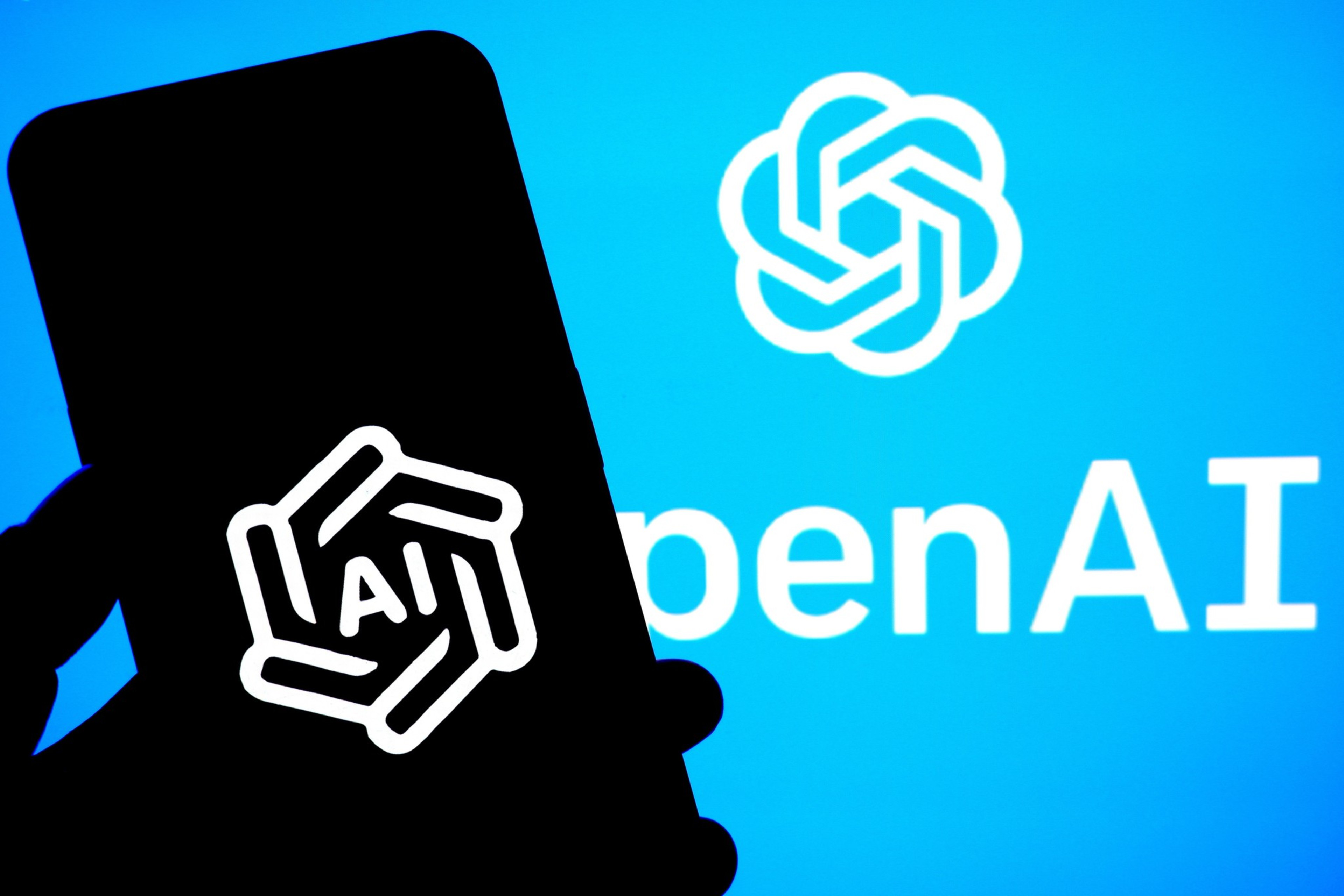 In this photo illustration, an OpenAI logo is seen displayed on a smartphone and in the background. | Avishek Das/SOPA Images/LightRocket via Getty Images