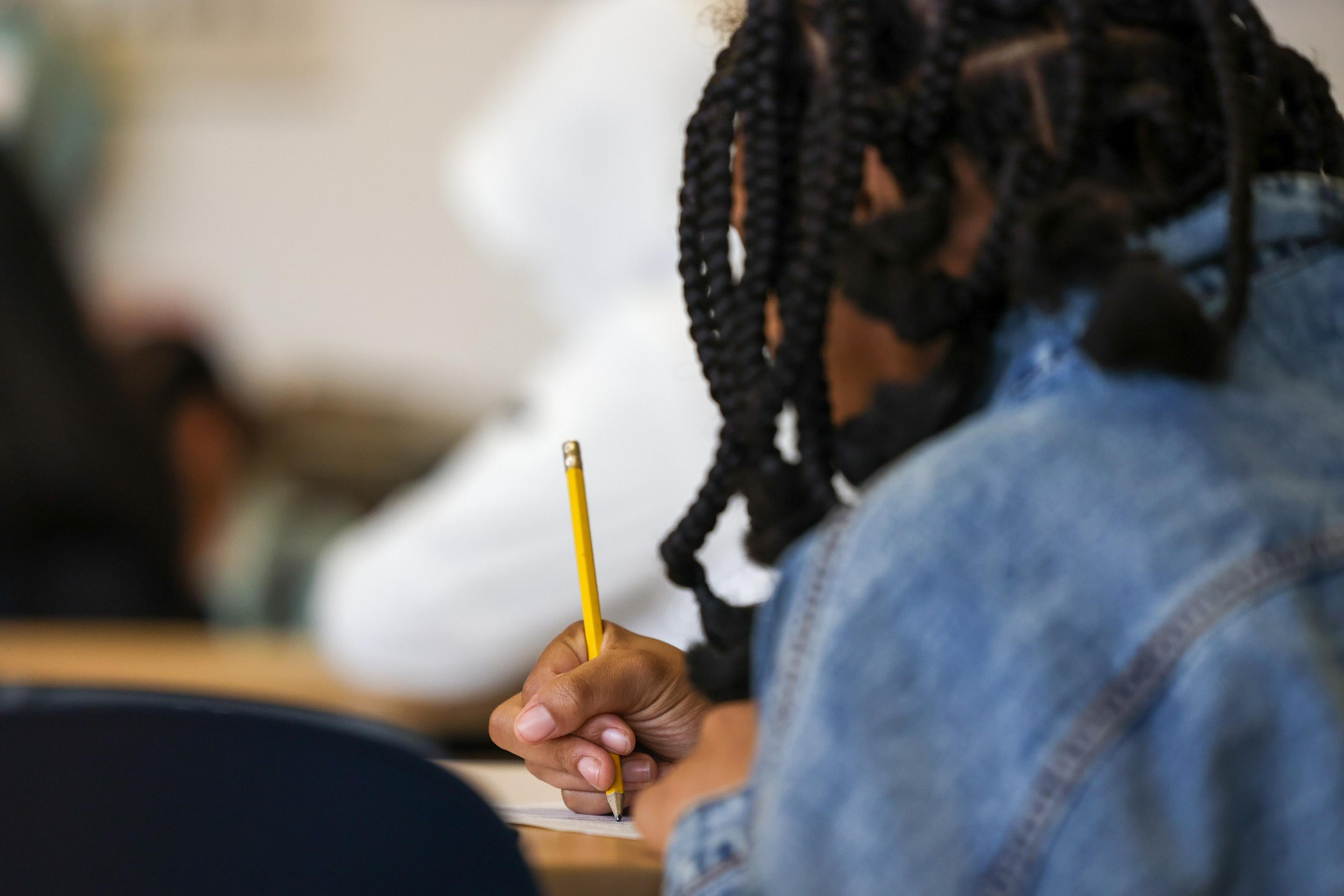 A student writes with a pencil.