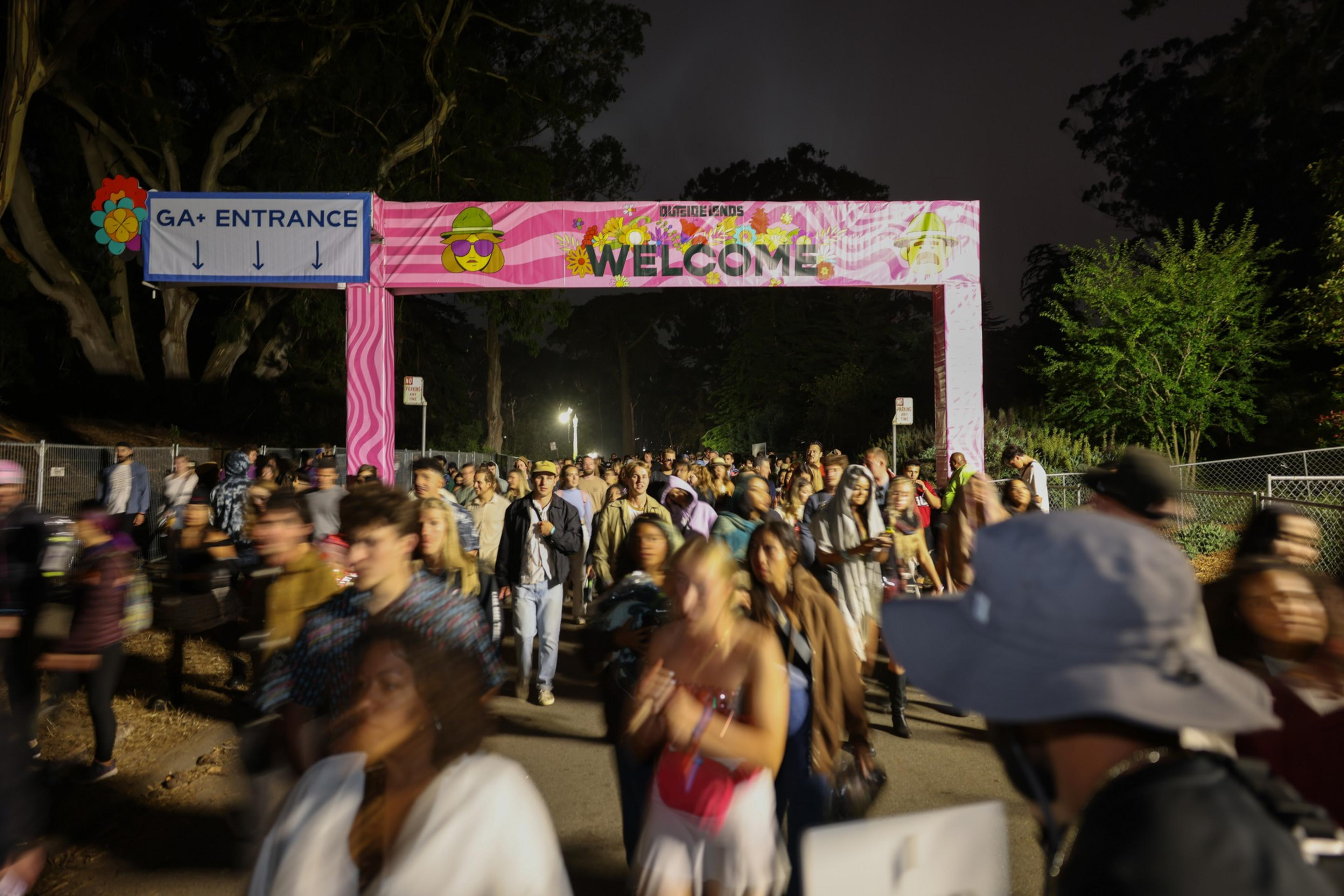 A large crowd of people exits the Outside Lands concert at night in San Francisco's Golden Gate Park.