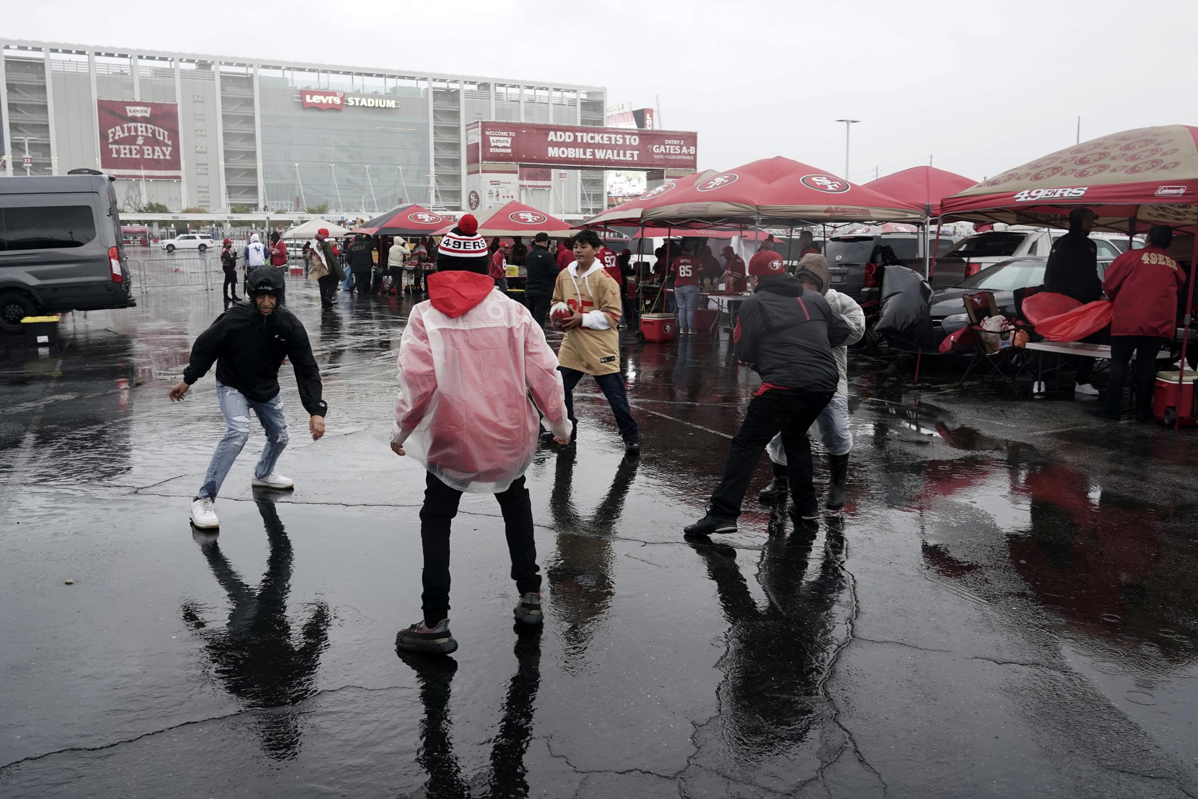 Fans walk in wet weather outside a staidum