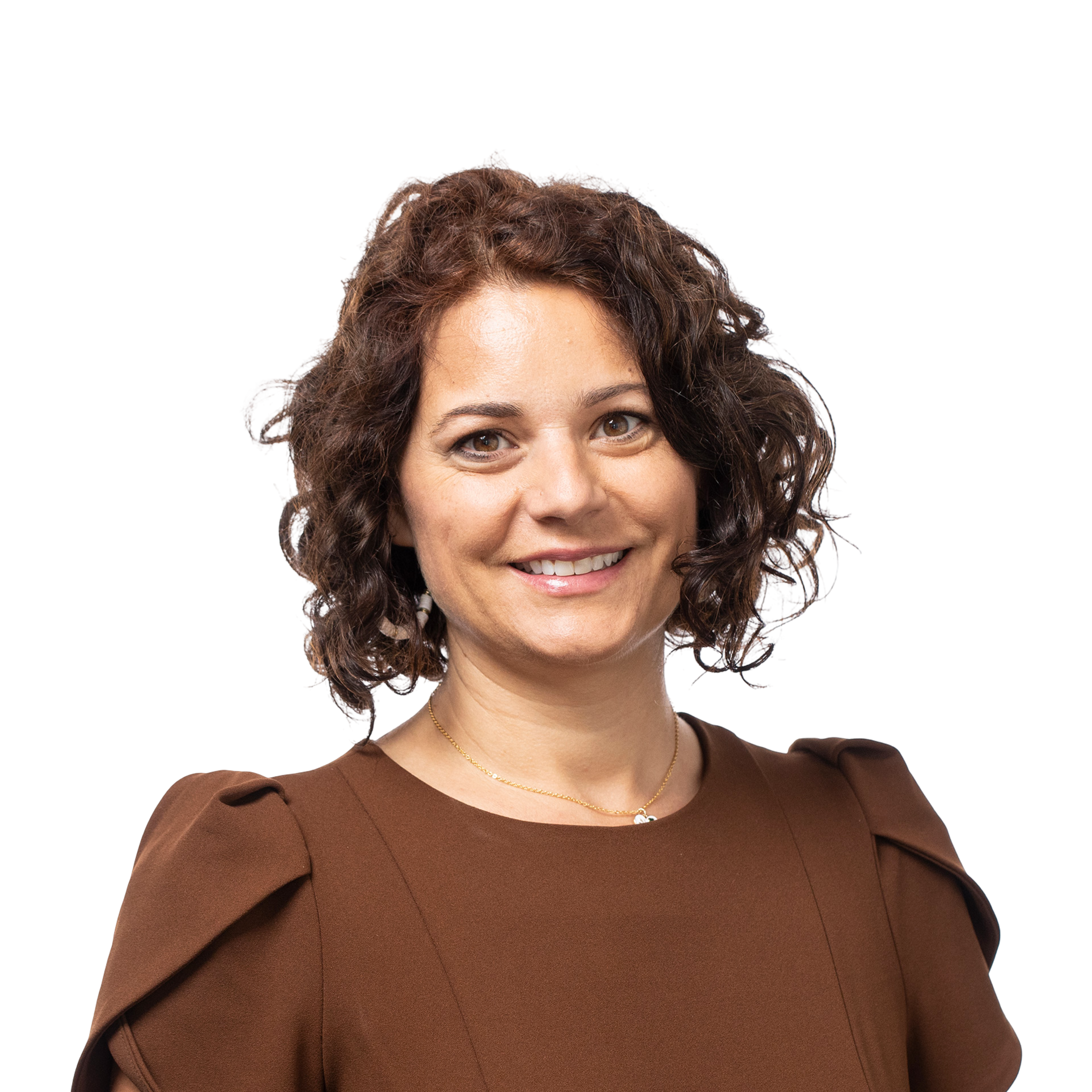A smiling woman with curly brown hair wears a brown dress with puffed shoulders and a delicate gold necklace.