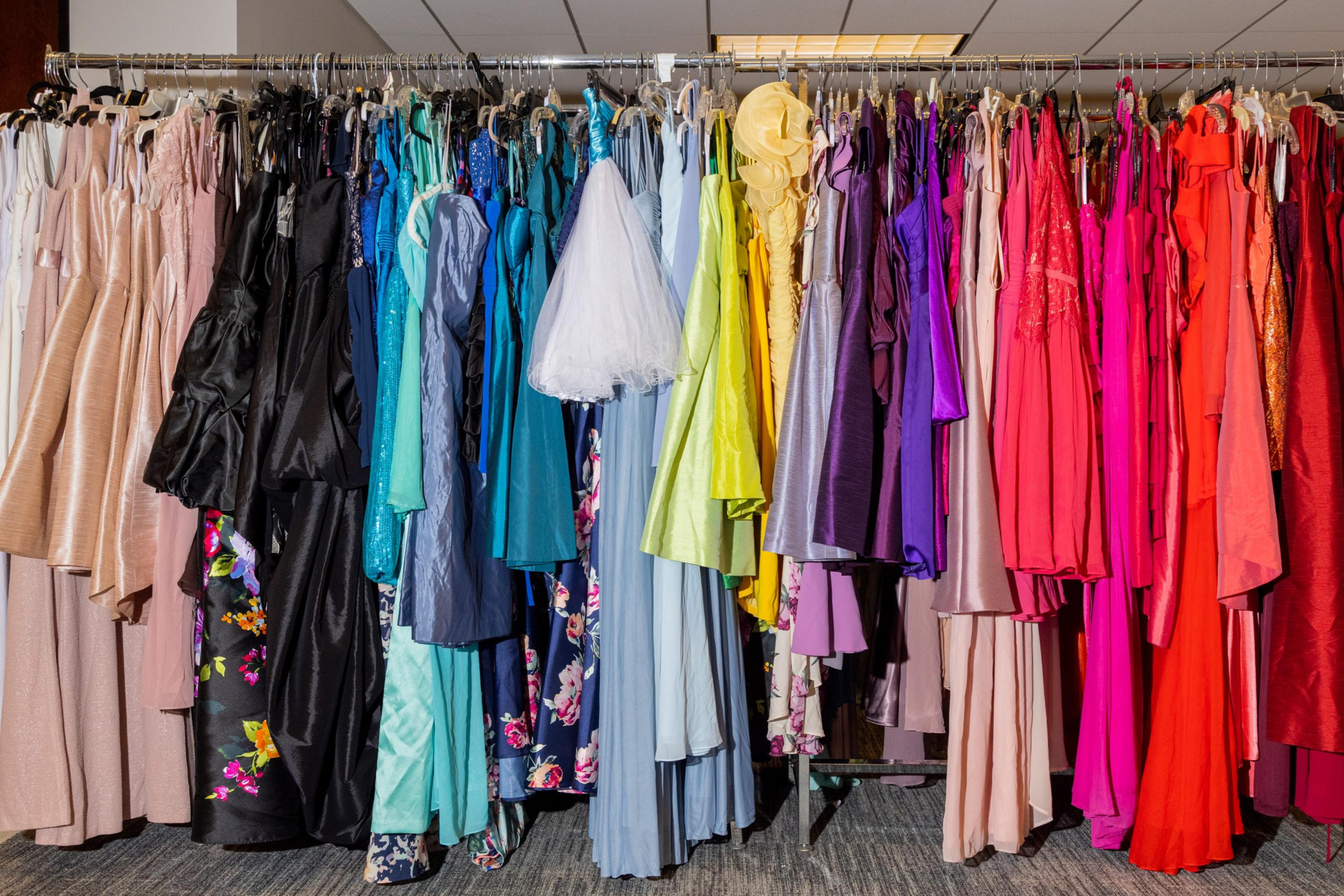 A range of colorful formal dresses hanging on racks in a store.