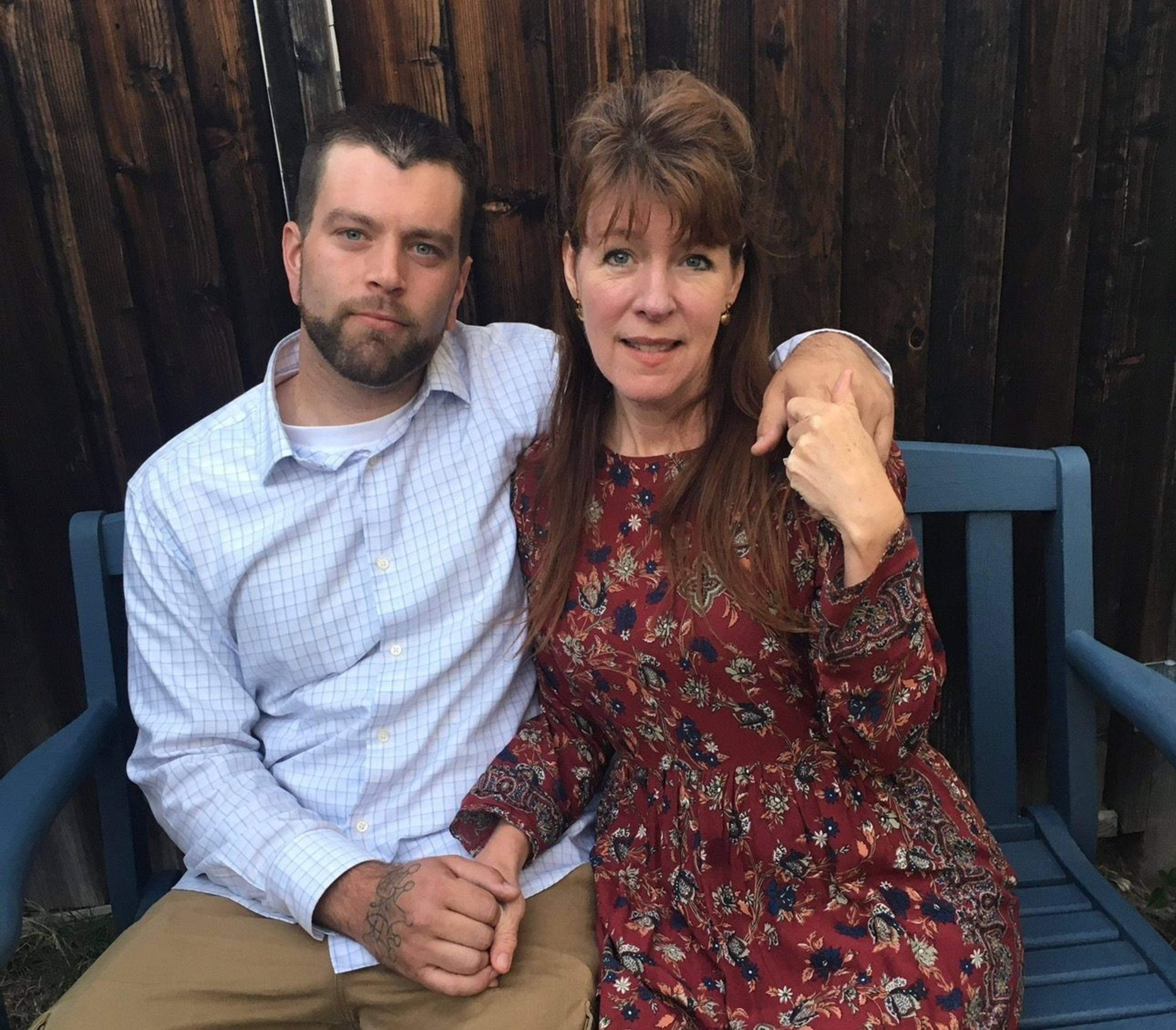 A man and woman sit on a bench, holding each other.