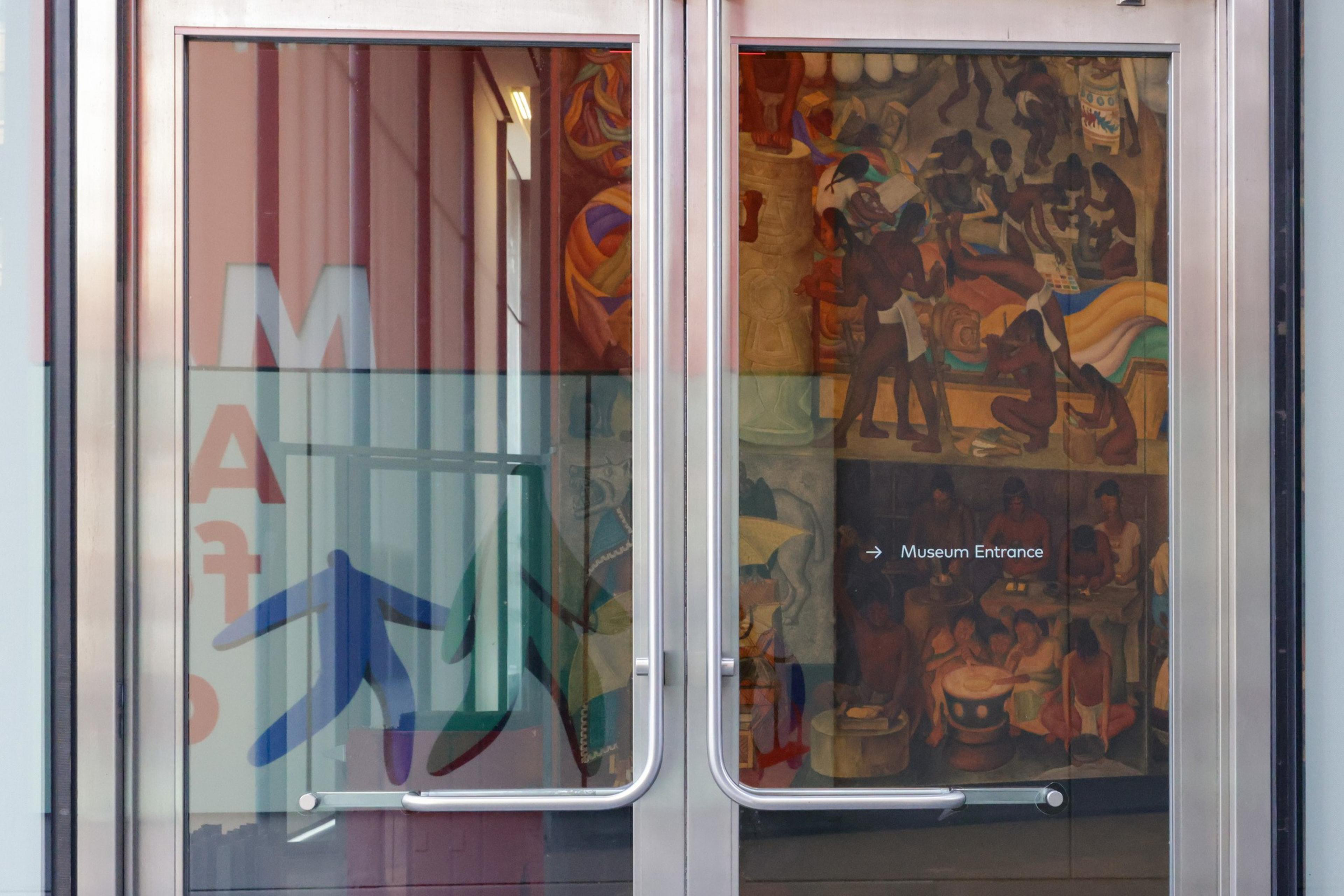 A mural is barely visible behind glass doors.