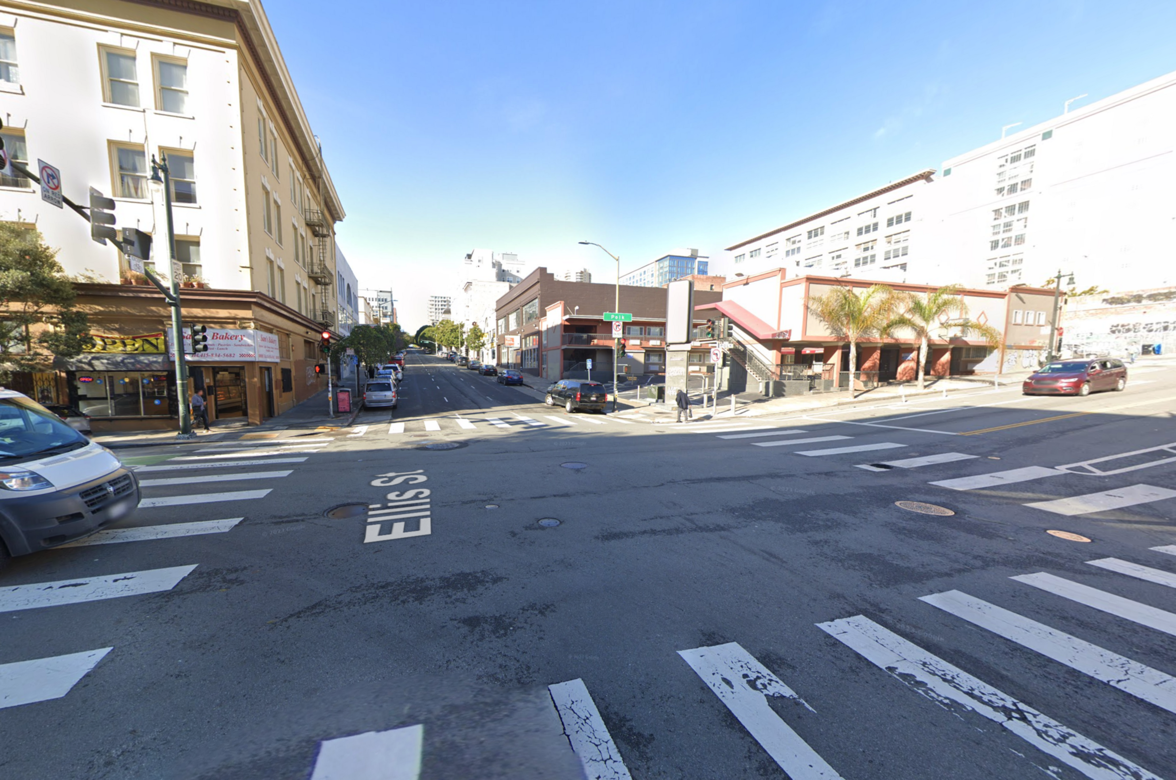 A four-way intersection is surrounded by commercial buildings and car traffic.