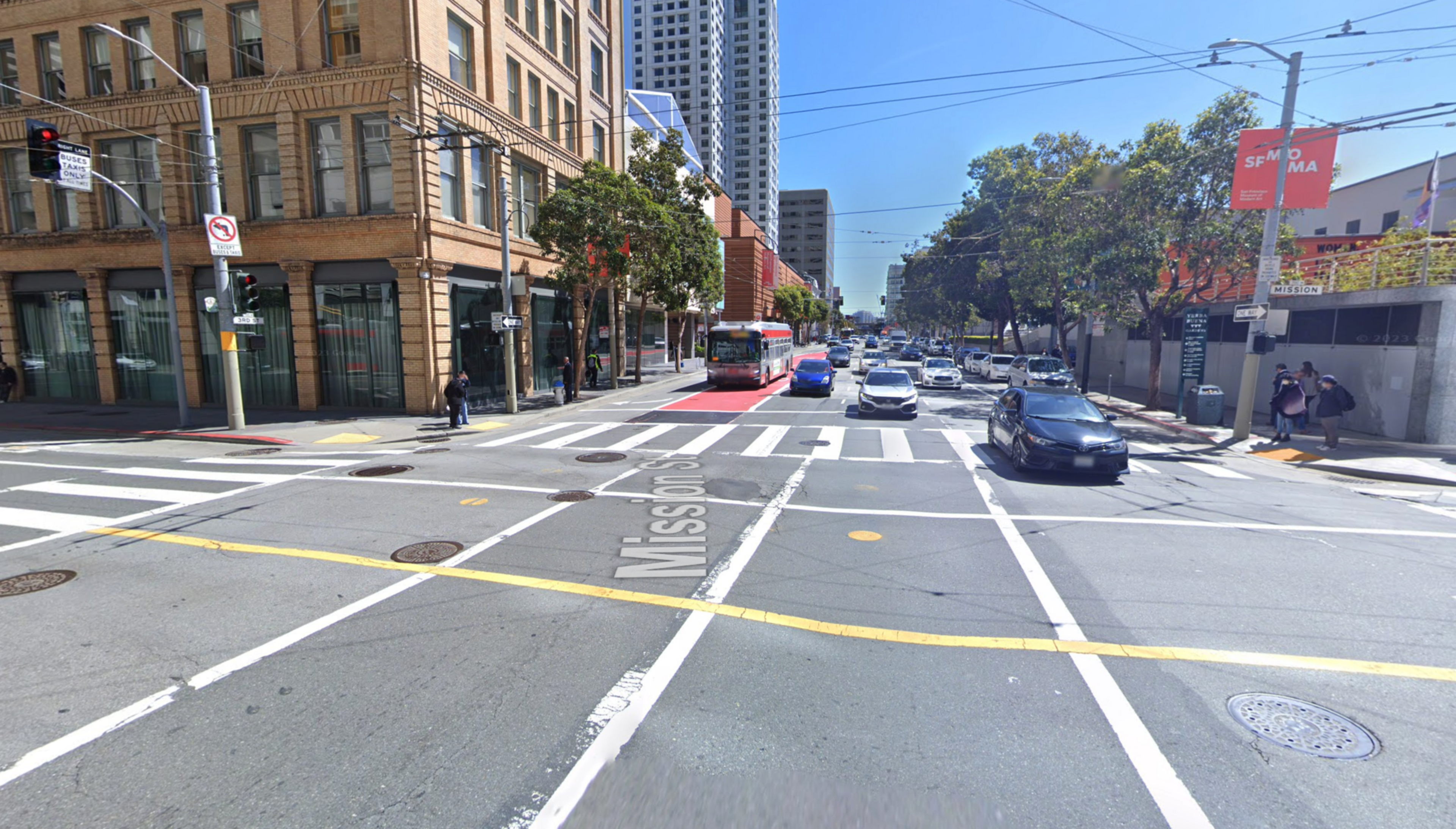 Cars wait at stop lights at a four-way intersection.