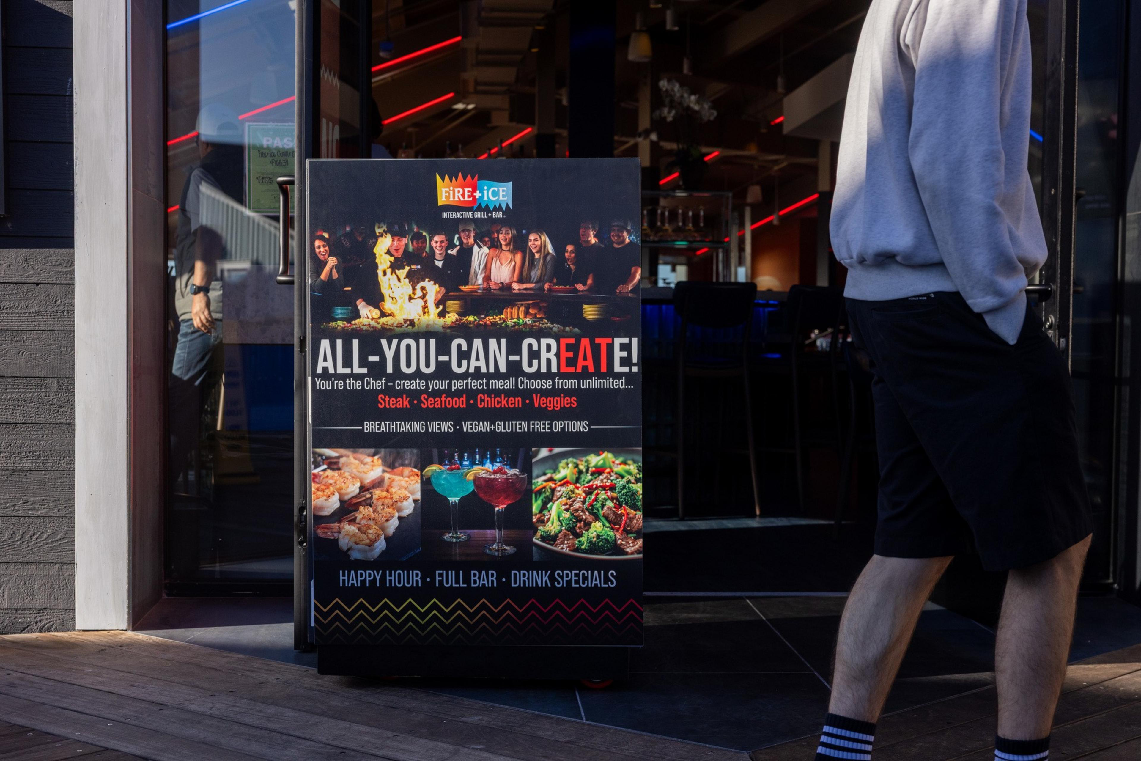 A restaurant sign advertises an all-you-can-create meal with steak, seafood, chicken, veggies, happy hour, full bar, and drink specials.