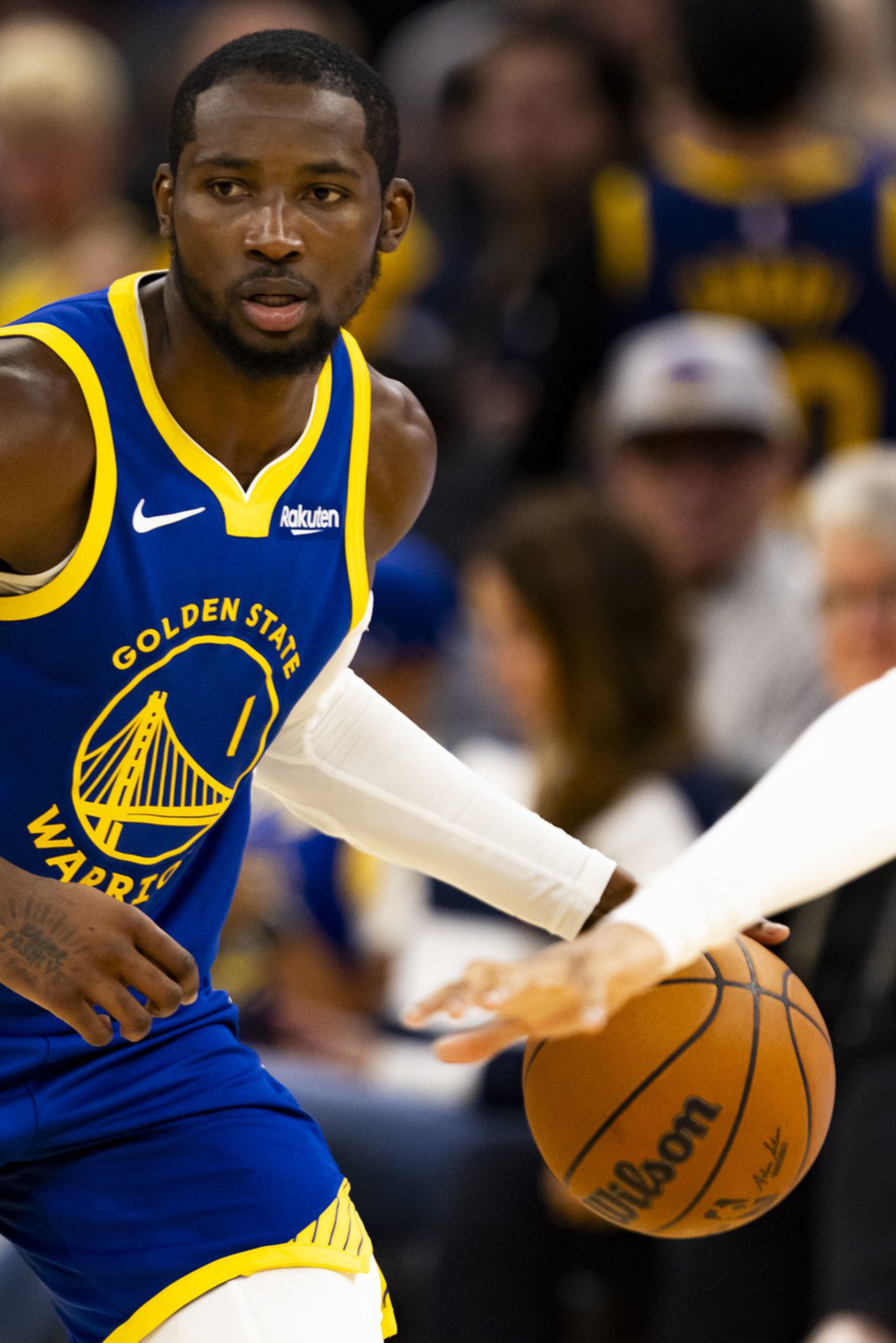 A Golden State Warriors player dribbles the basketball while guarded closely by a Phoenix Suns player during a game.
