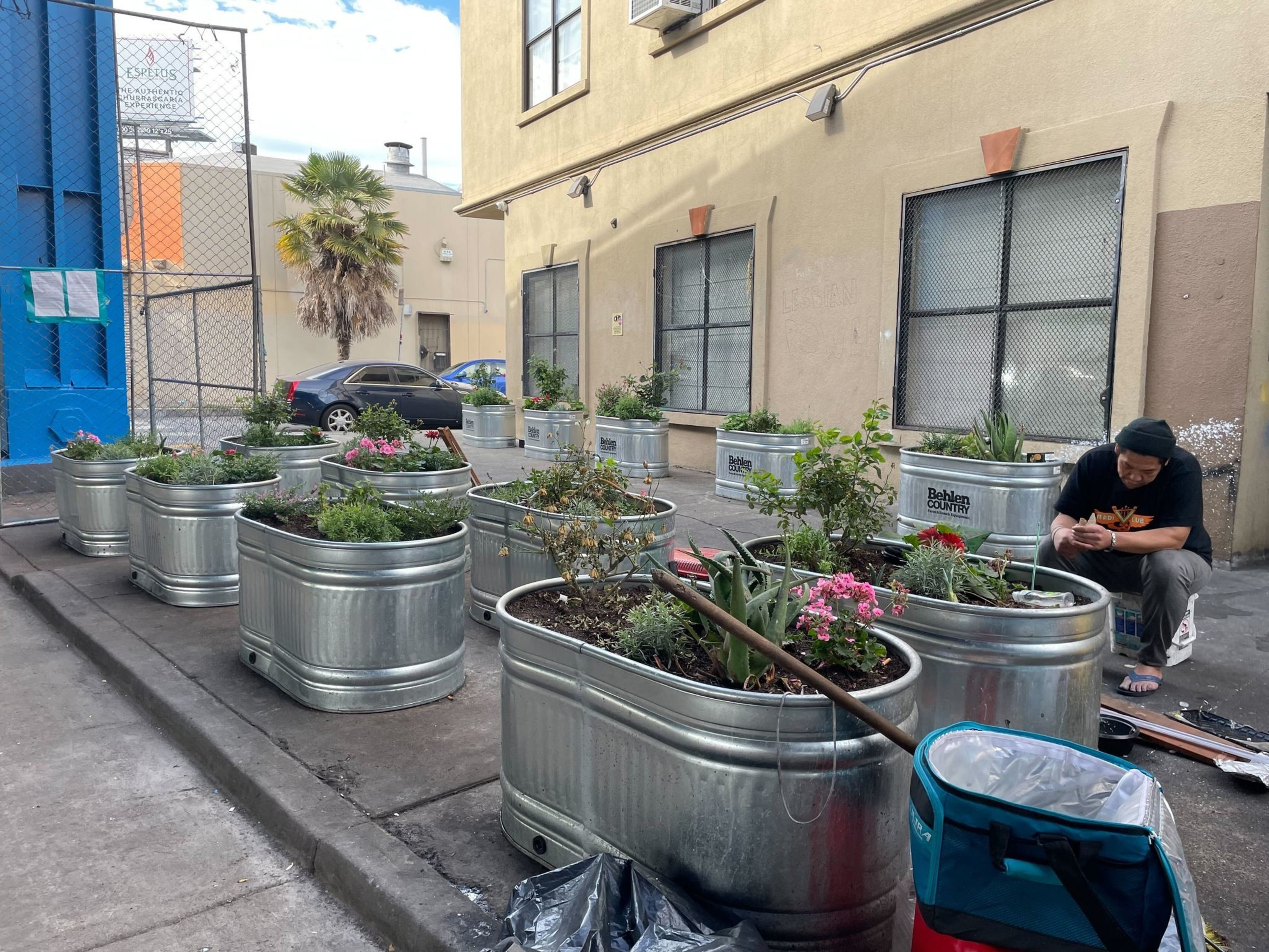 Large, metal planters sit on a sidewalk.