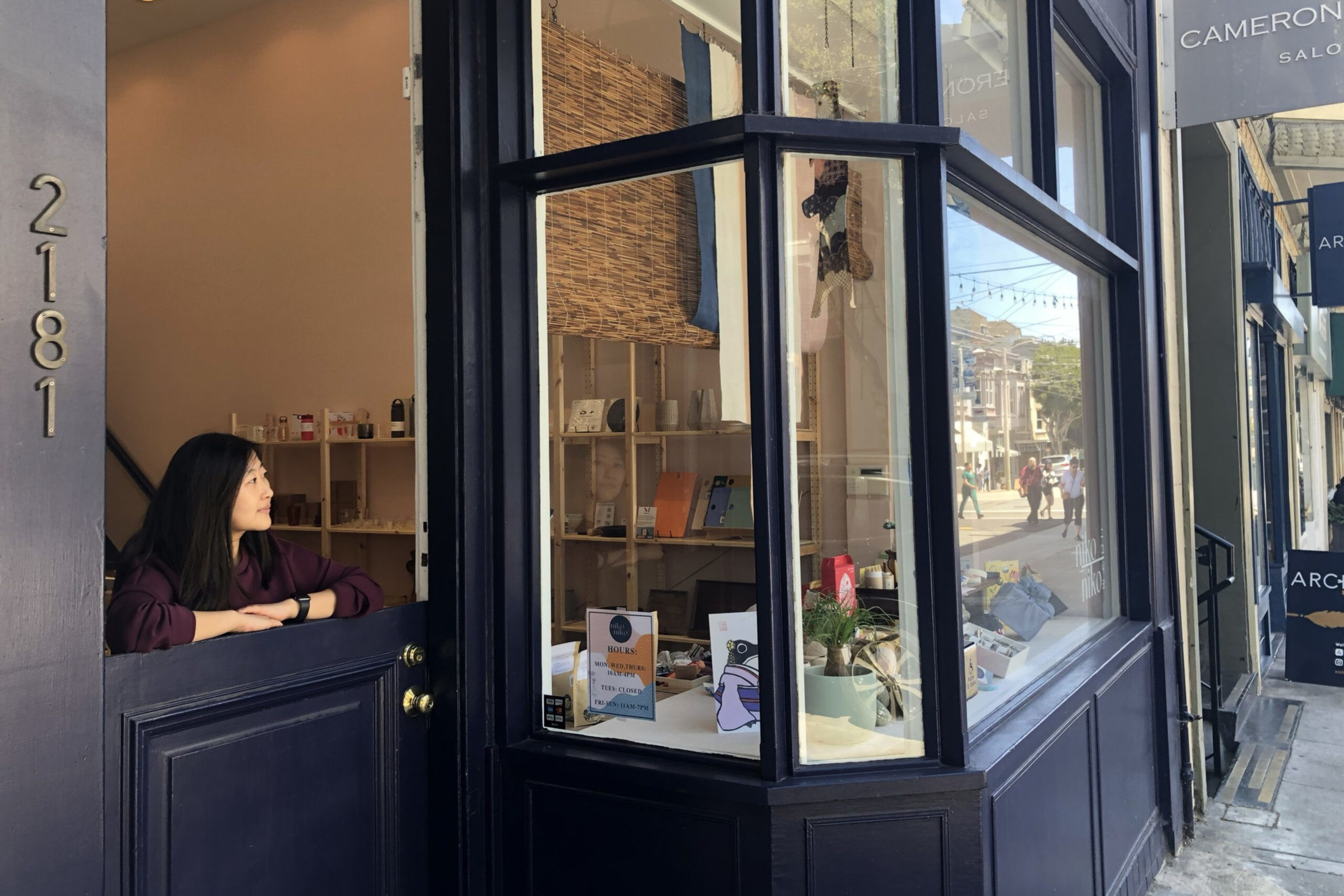A woman looks out from a blue storefront onto Union Street in San Francisco, California.