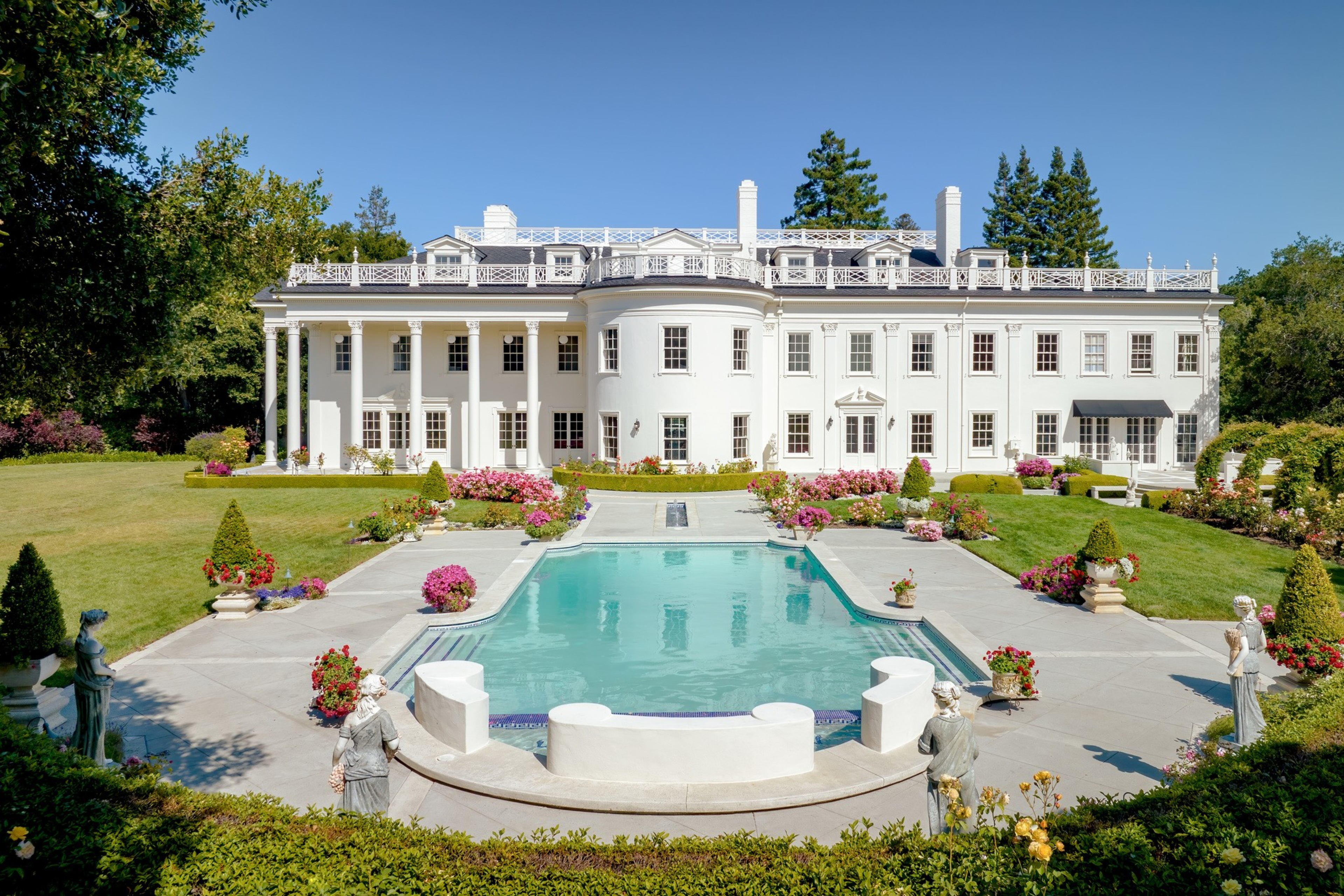 A swimming pool shimmers in sunlight in front of a large white building