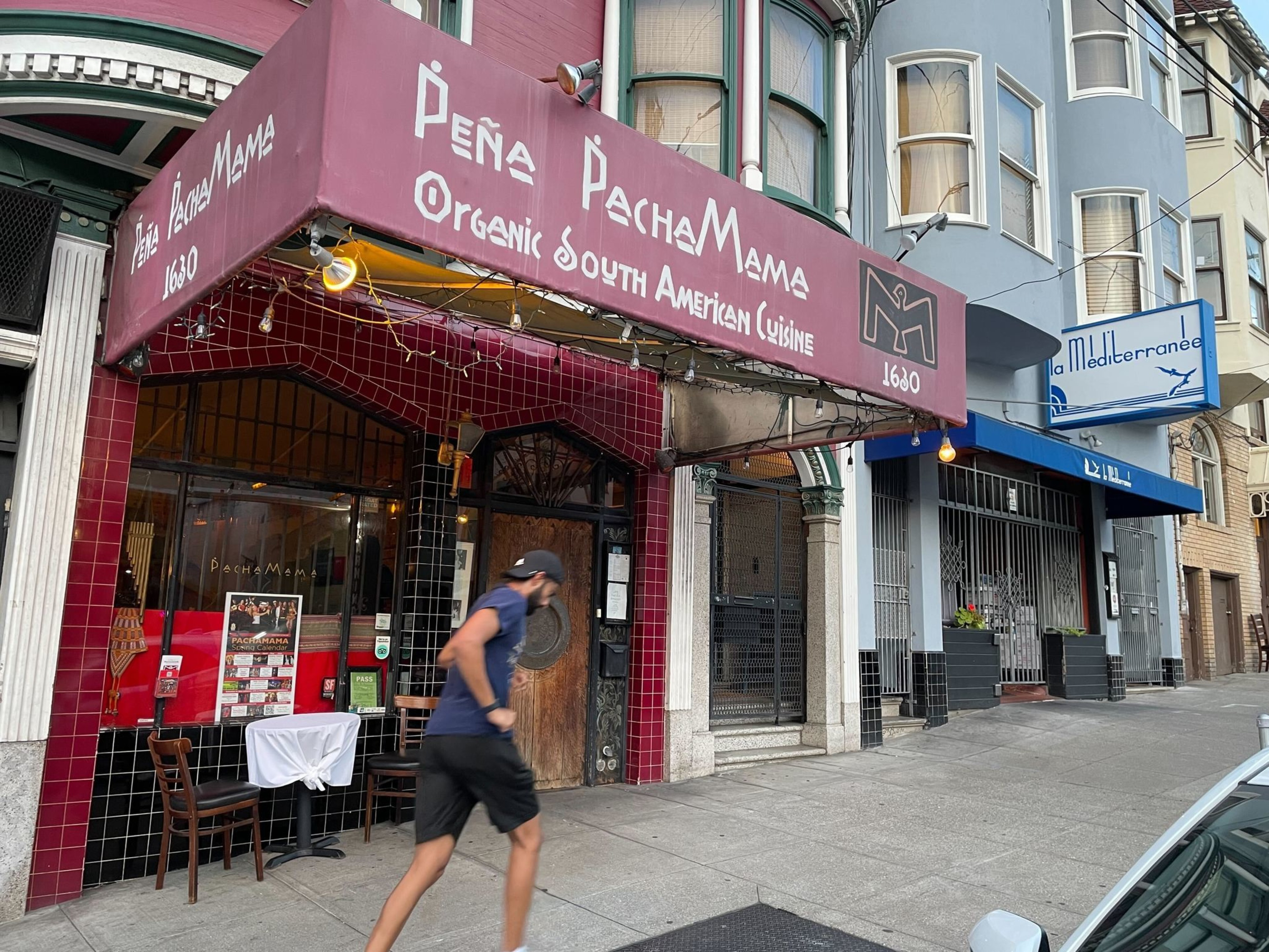 A man runs past a restaurant.