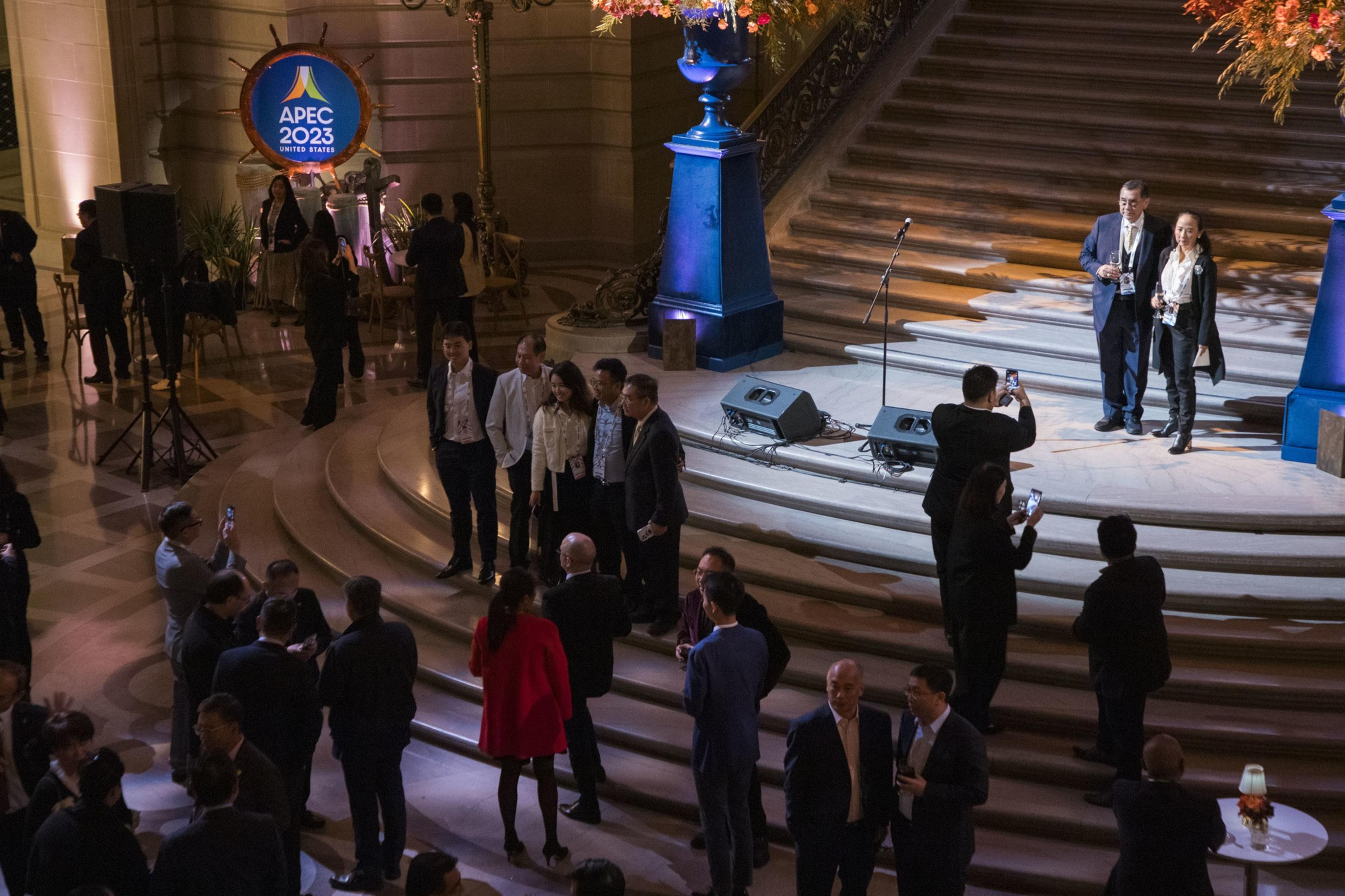 People scattered throughout city hall taking pictures and talking with one another at a welcome party for APEC.