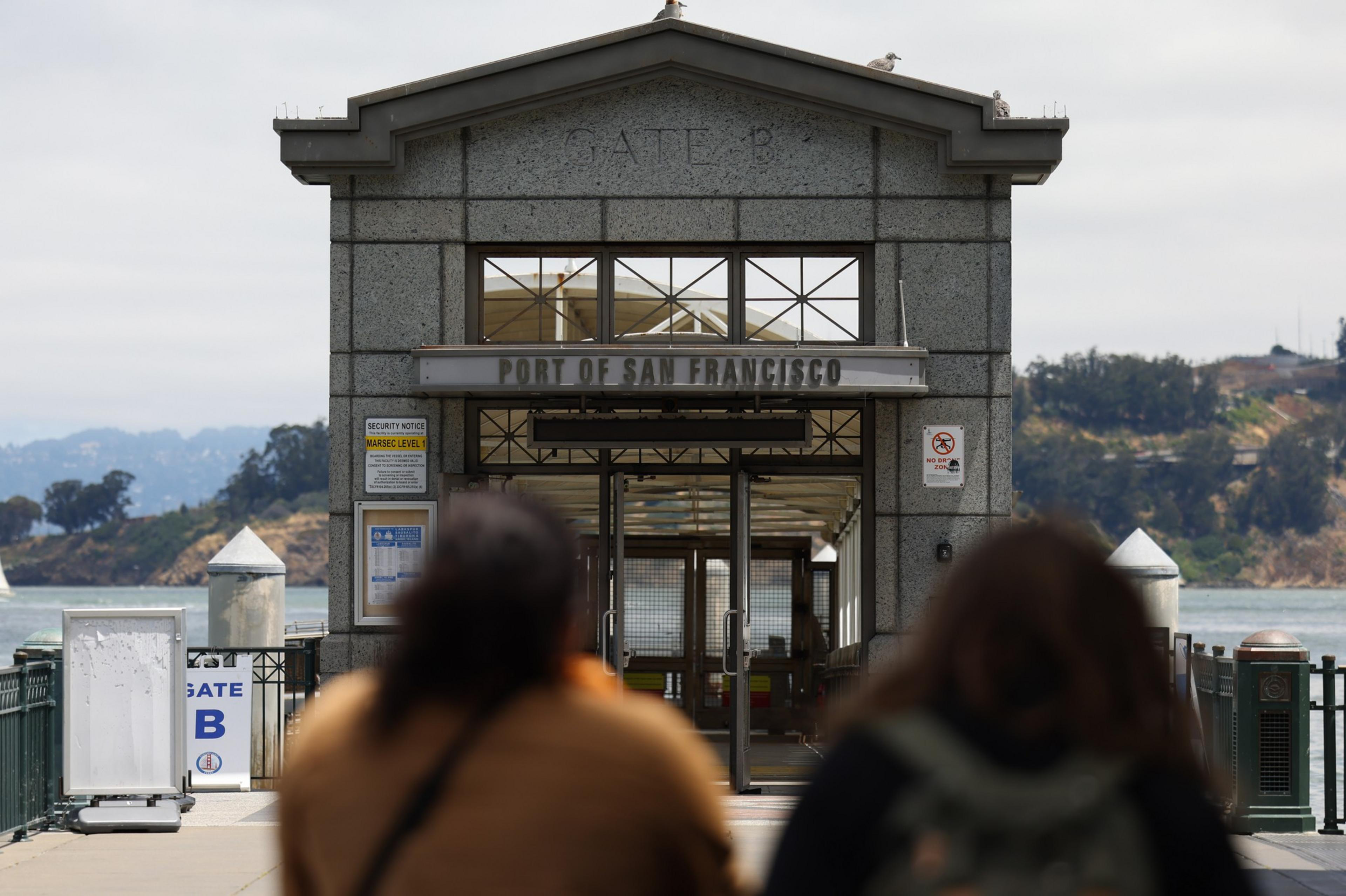 Two people face the entrance to a dock to the Port of San Francisco. 