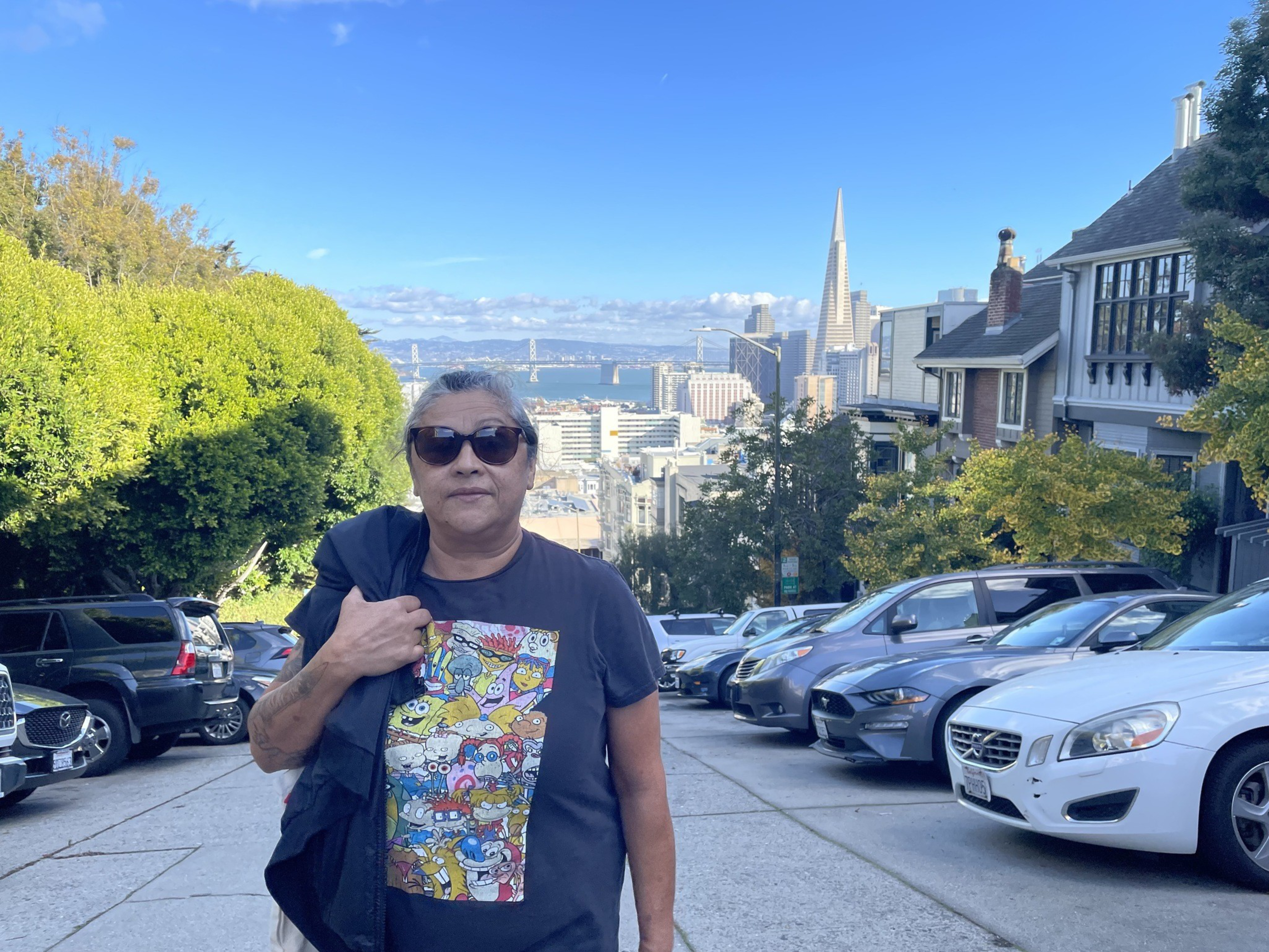 A woman stands on a hill with Downtown San Francisco behind her.