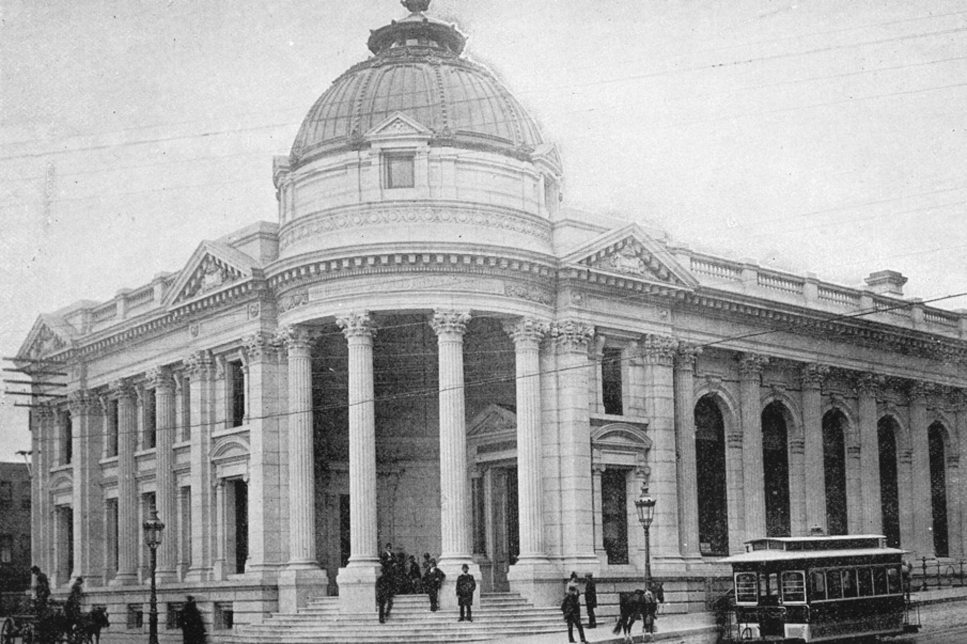 The image depicts a grand neoclassical building with a large dome, columns, and steps, alongside a street with a horse-drawn streetcar and people nearby.
