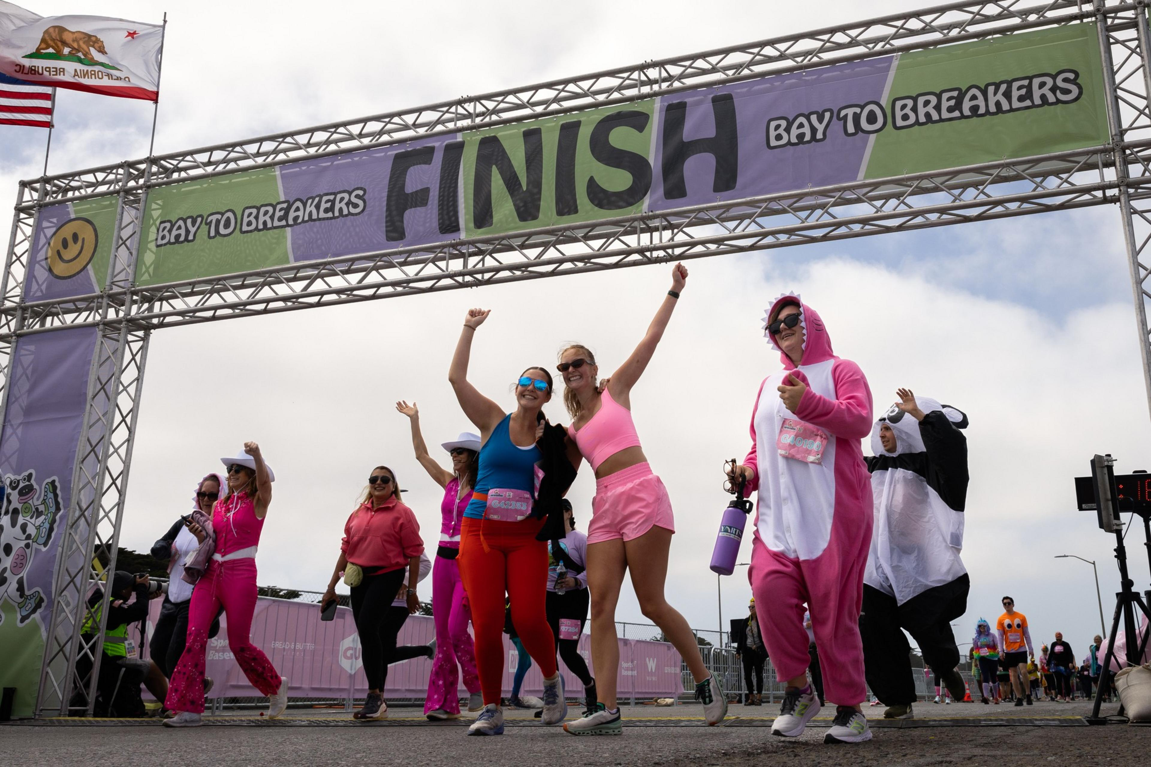 Runners cross a foot race finish line with jubilant shouts and joyfully gestures