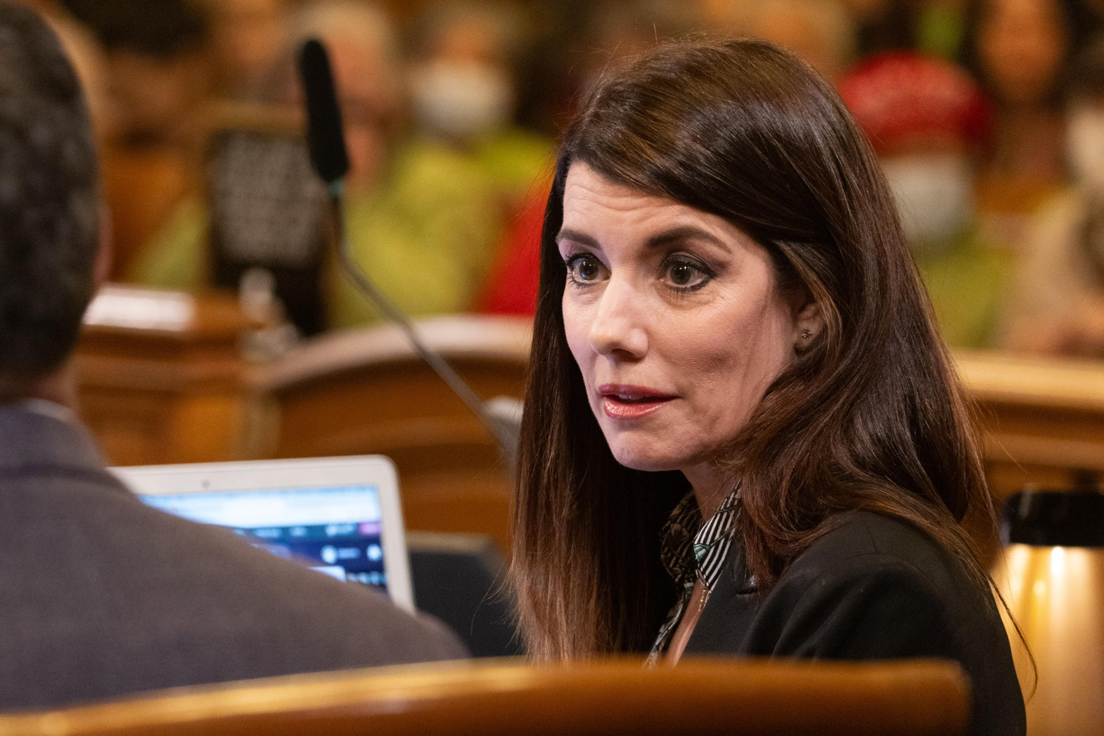 Supervisor Catherine Stefani in her chair talks with another Board of Supervisor during public comment at city hall.