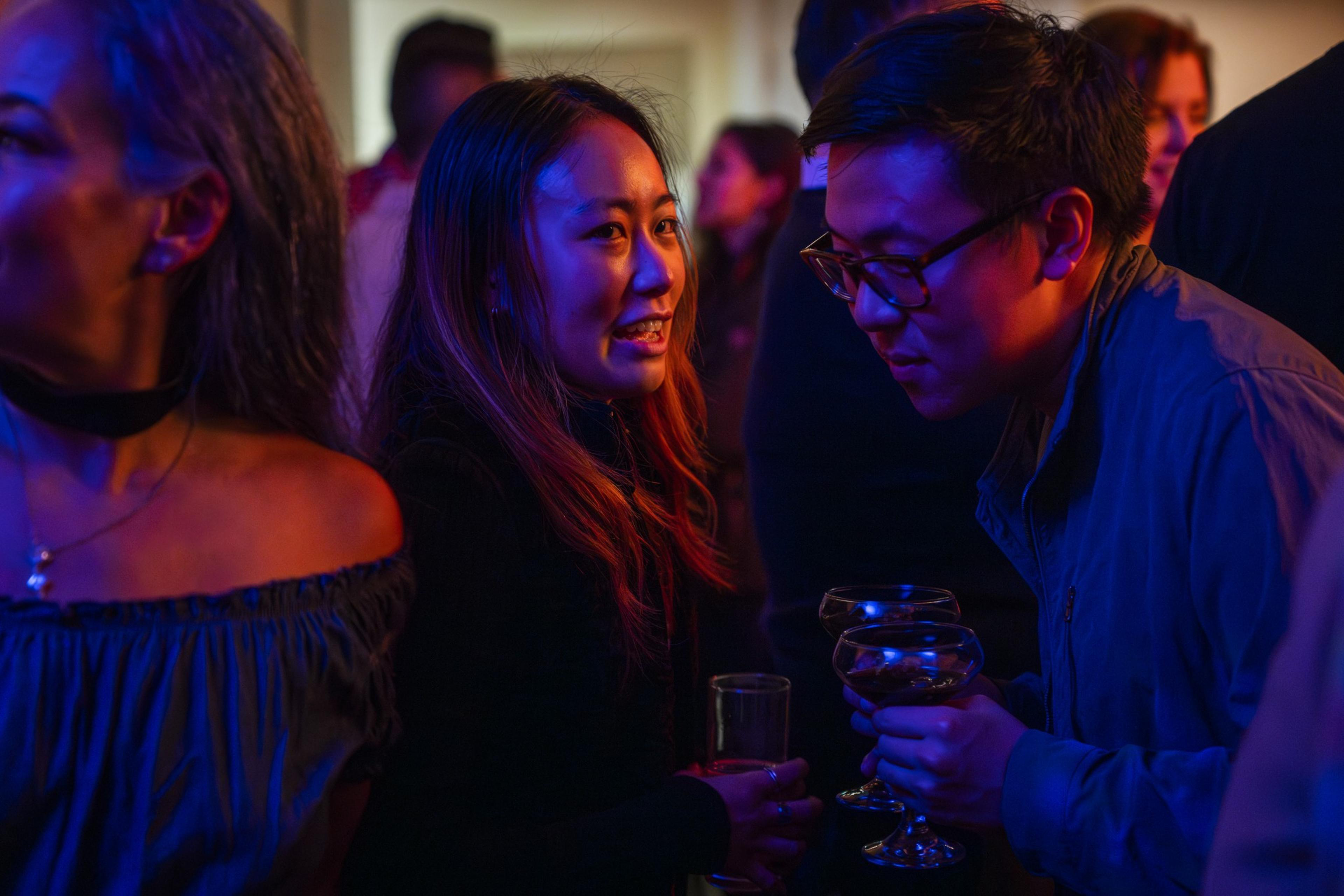 A man leans close to a woman to listen to her conversation a low lit bar in San Francisco.