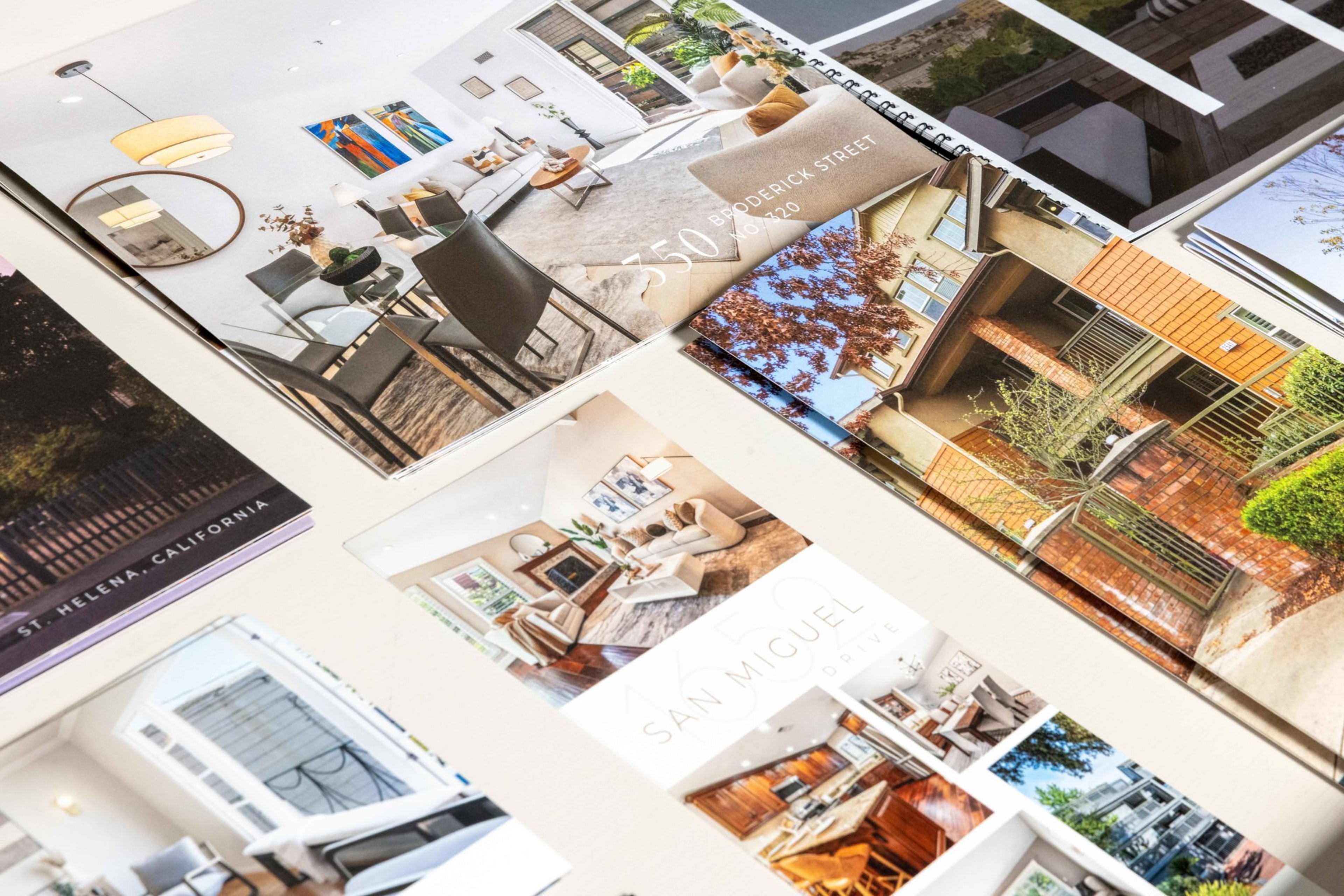 Brochures displaying various modern homes and interior designs are spread out on a light surface.