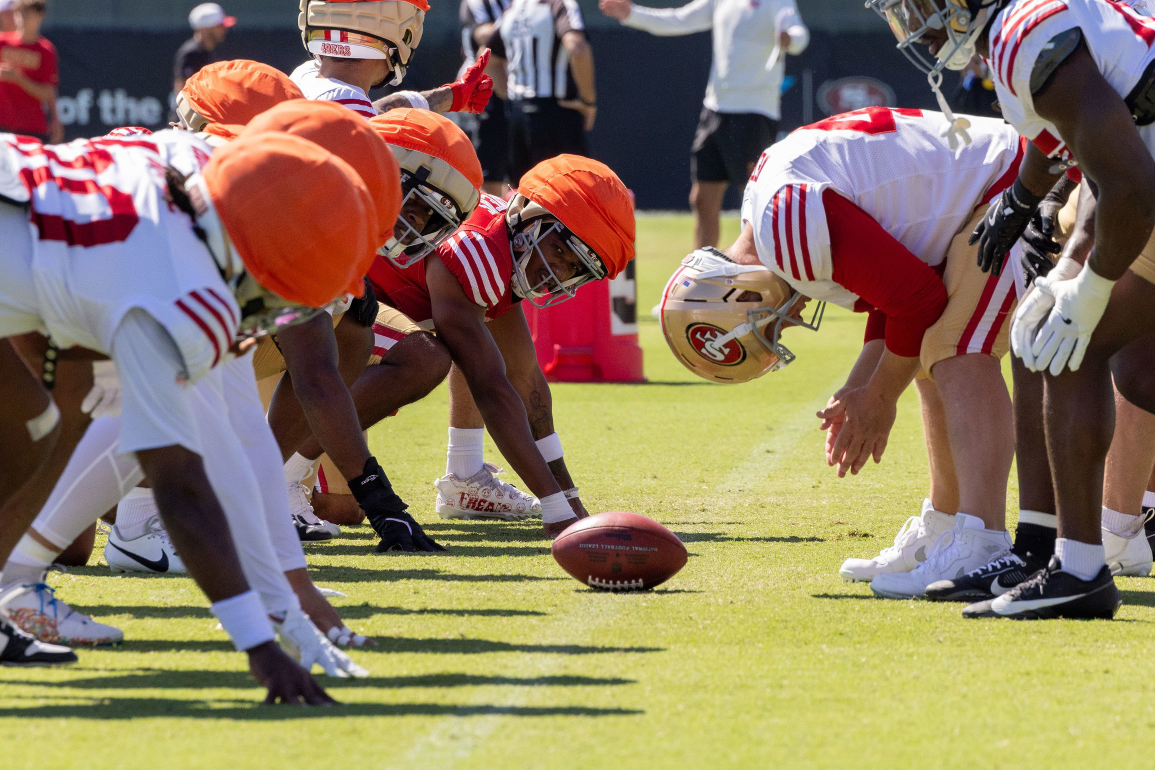 Two football teams lined up at the line of scrimmage preparing for a snap during a practice or game.