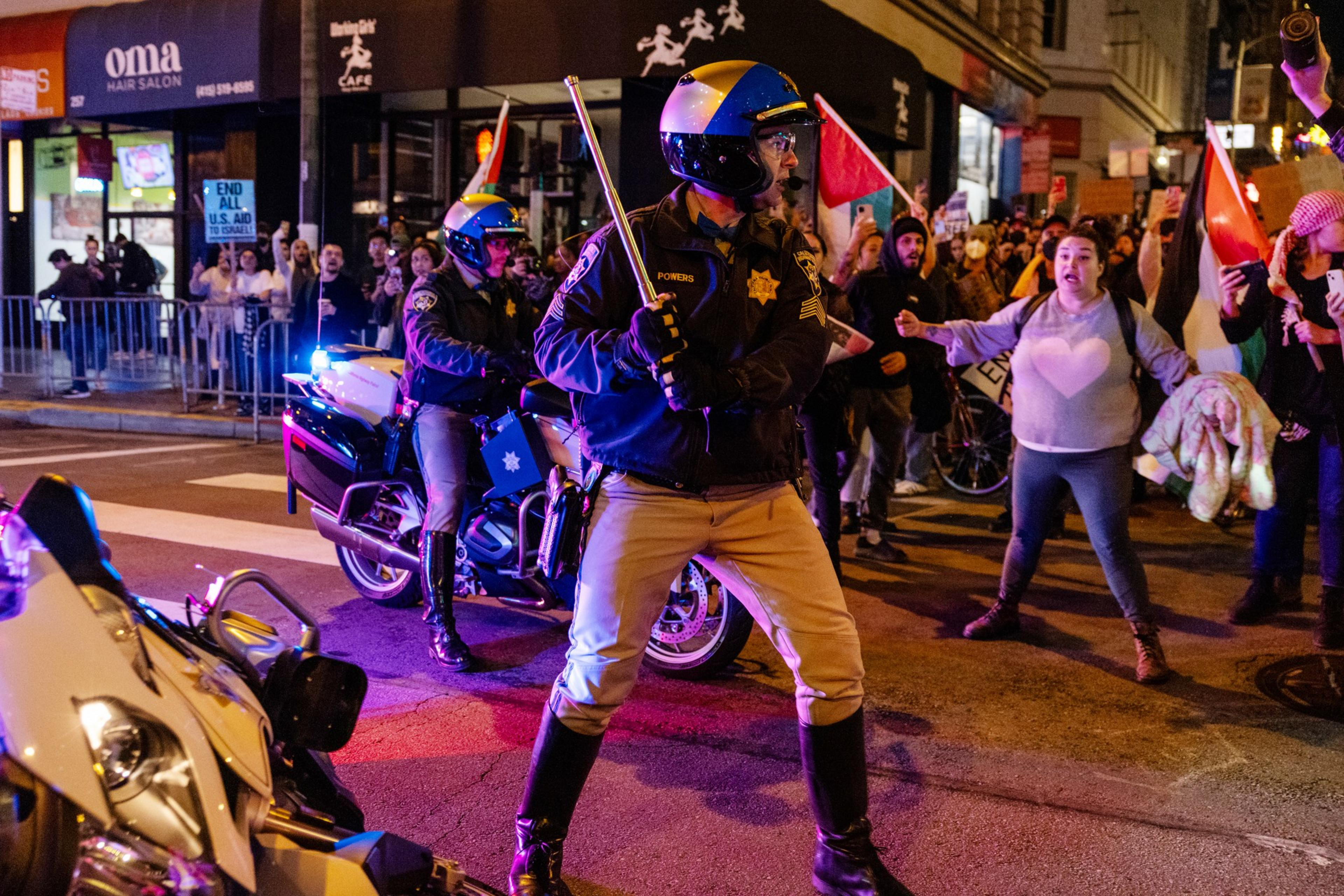 A California Highway Patrol Officer holds a baton as protesters scream during a demonstration.
