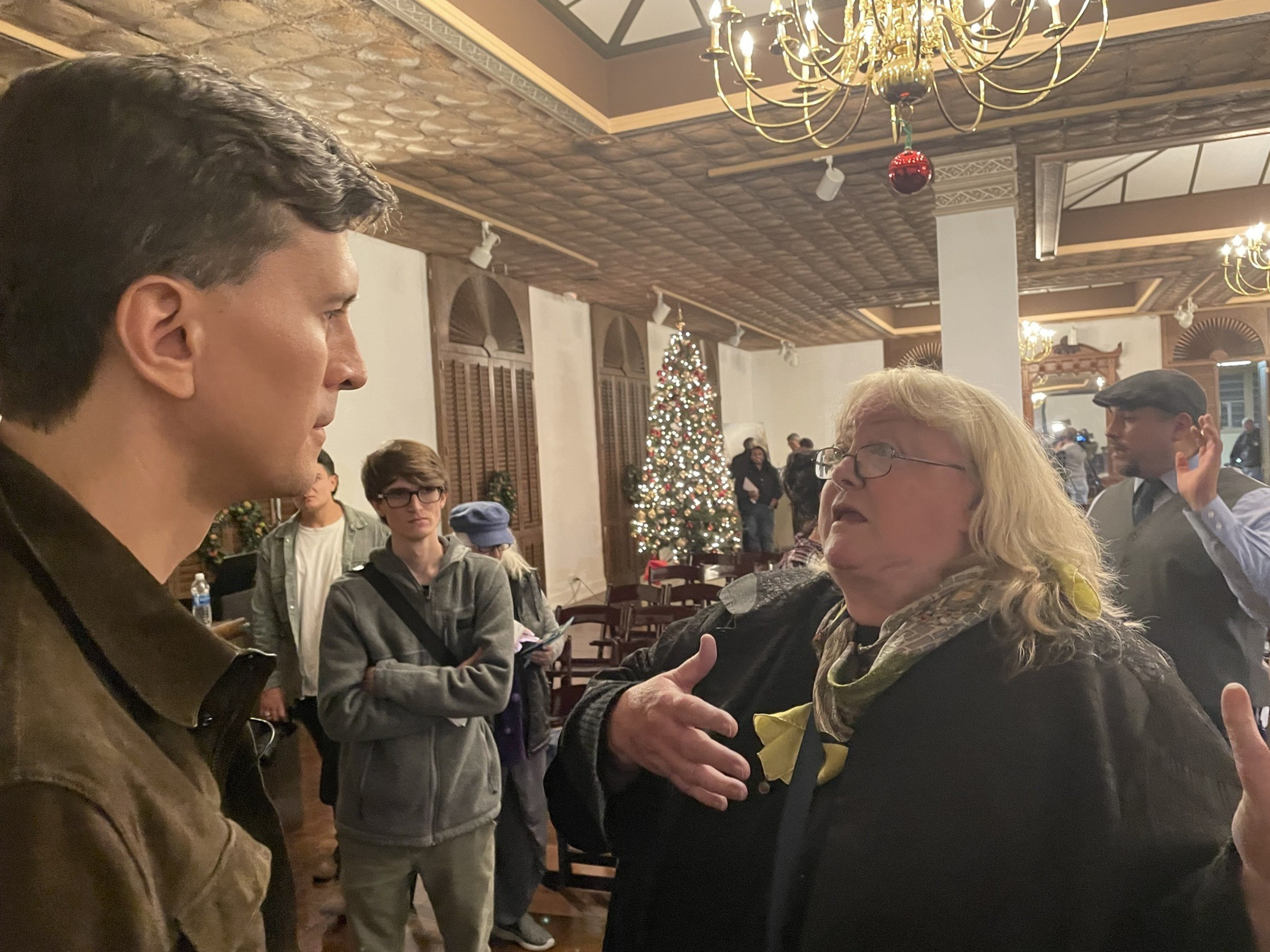 A woman gestures while speaking with a man.