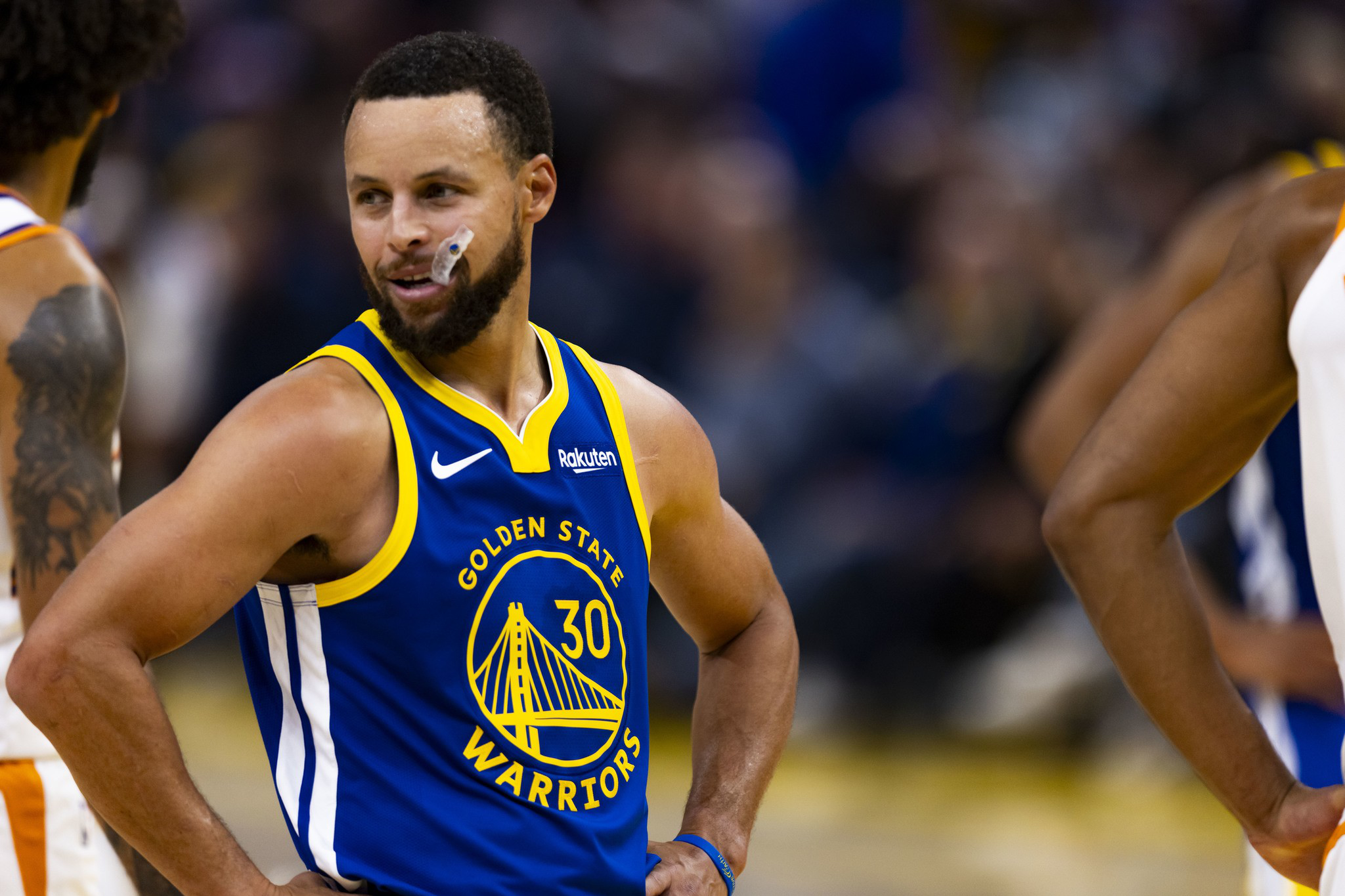 A basketball player in a blue Golden State Warriors jersey with number 30 smiles with hands on hips during a game.