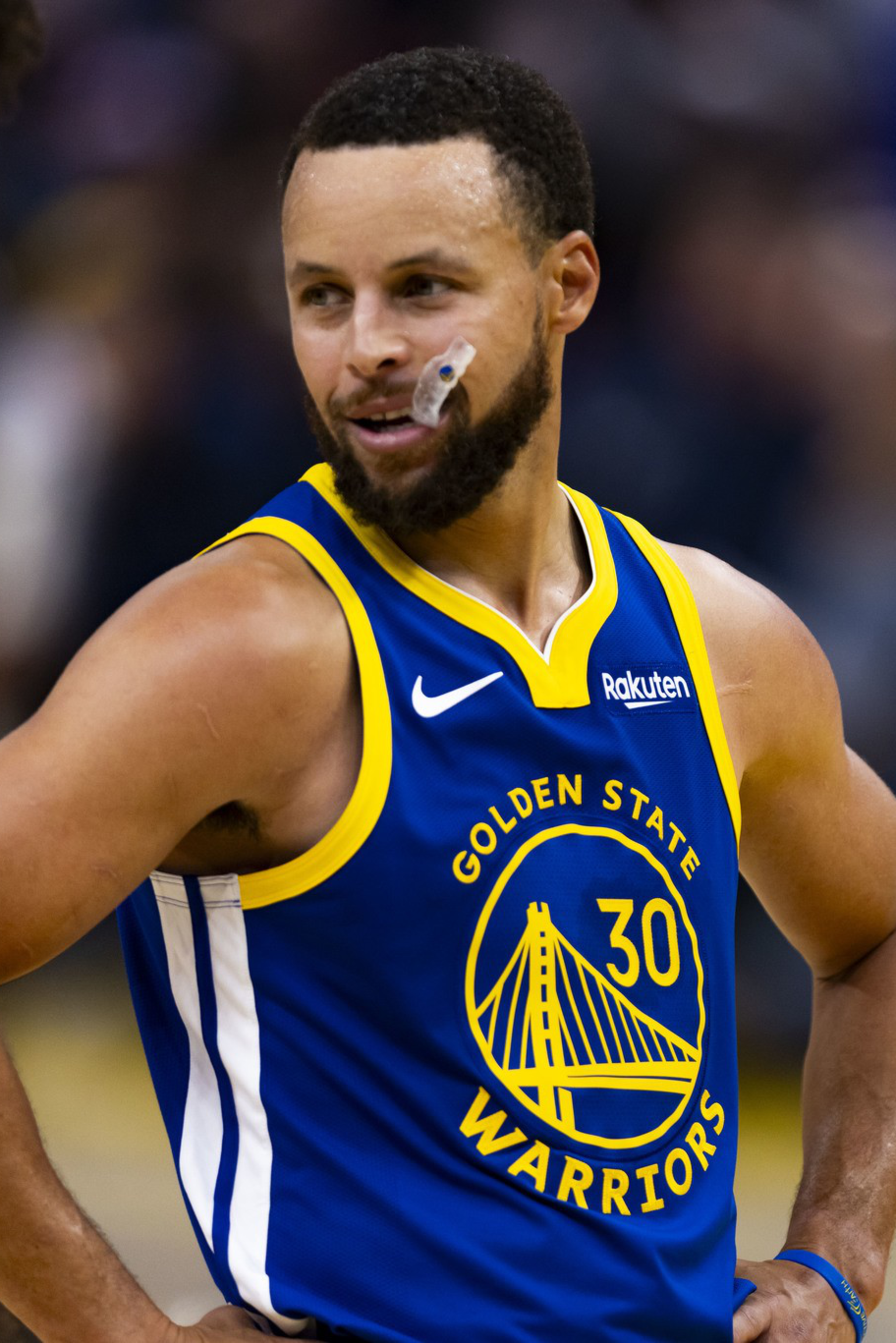 A basketball player in a blue Golden State Warriors jersey with number 30 smiles with hands on hips during a game.