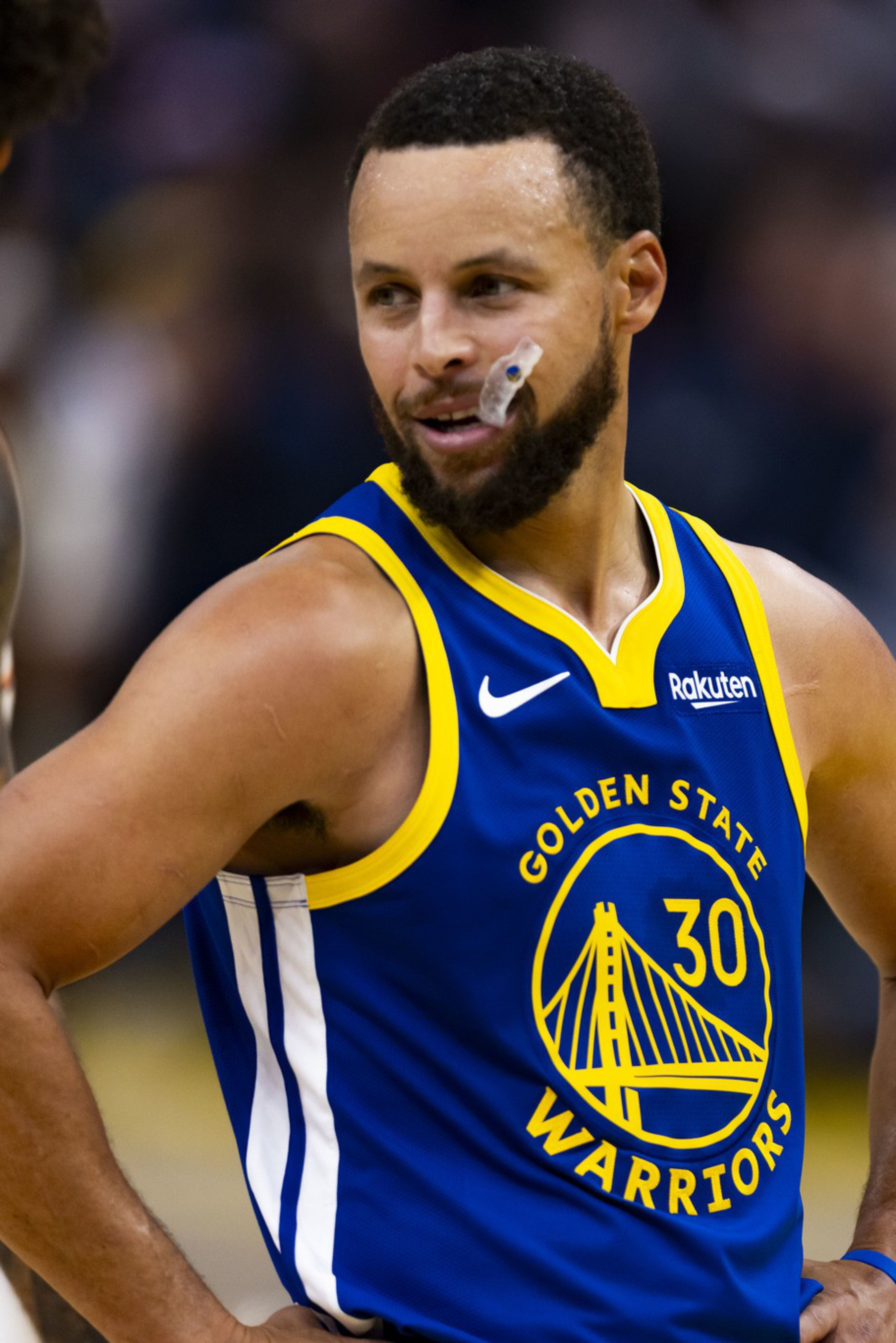 A basketball player in a blue Golden State Warriors jersey with number 30 smiles with hands on hips during a game.