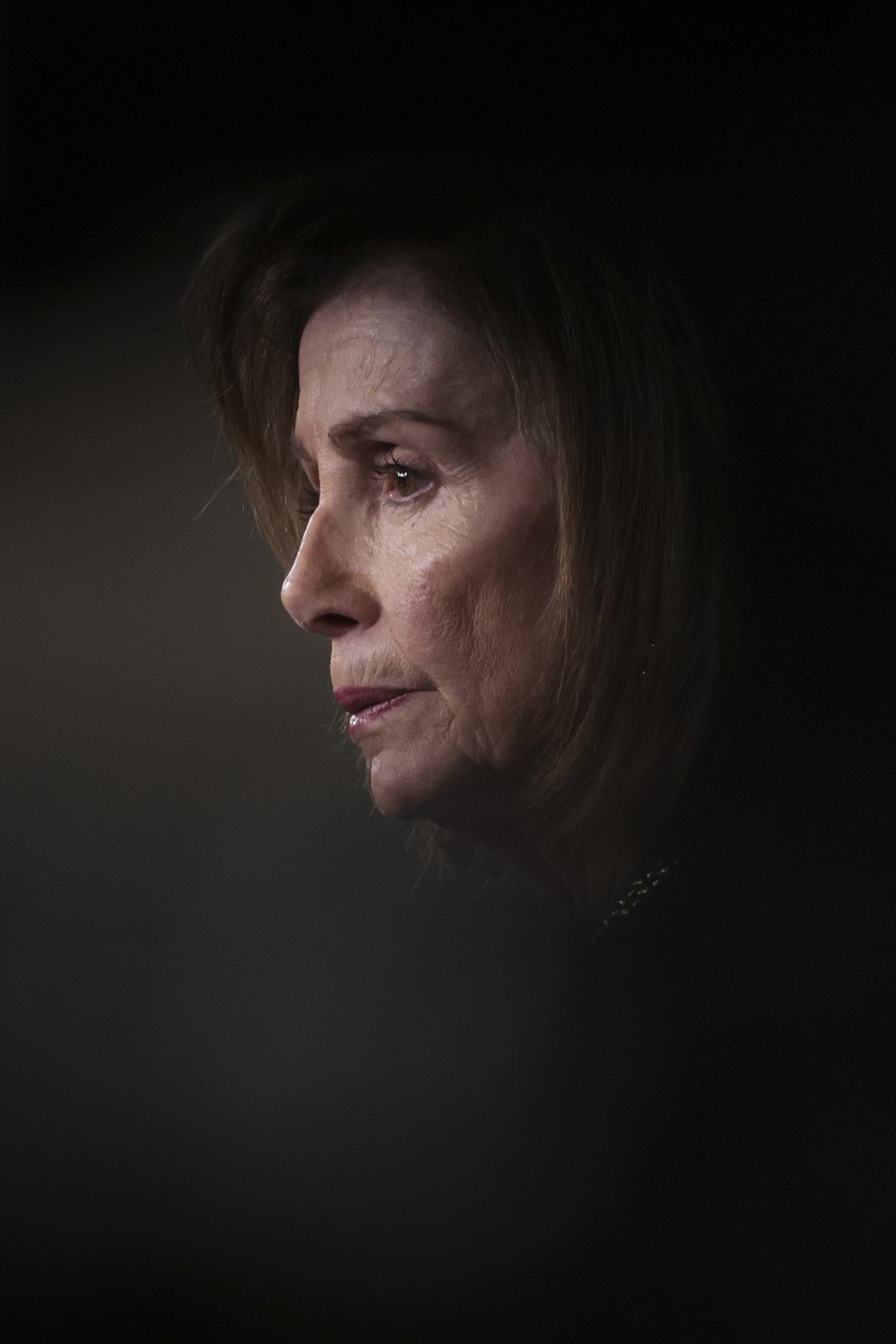 A person is seen in profile with soft lighting highlighting their face against a dark, blurred background. The expression appears contemplative.