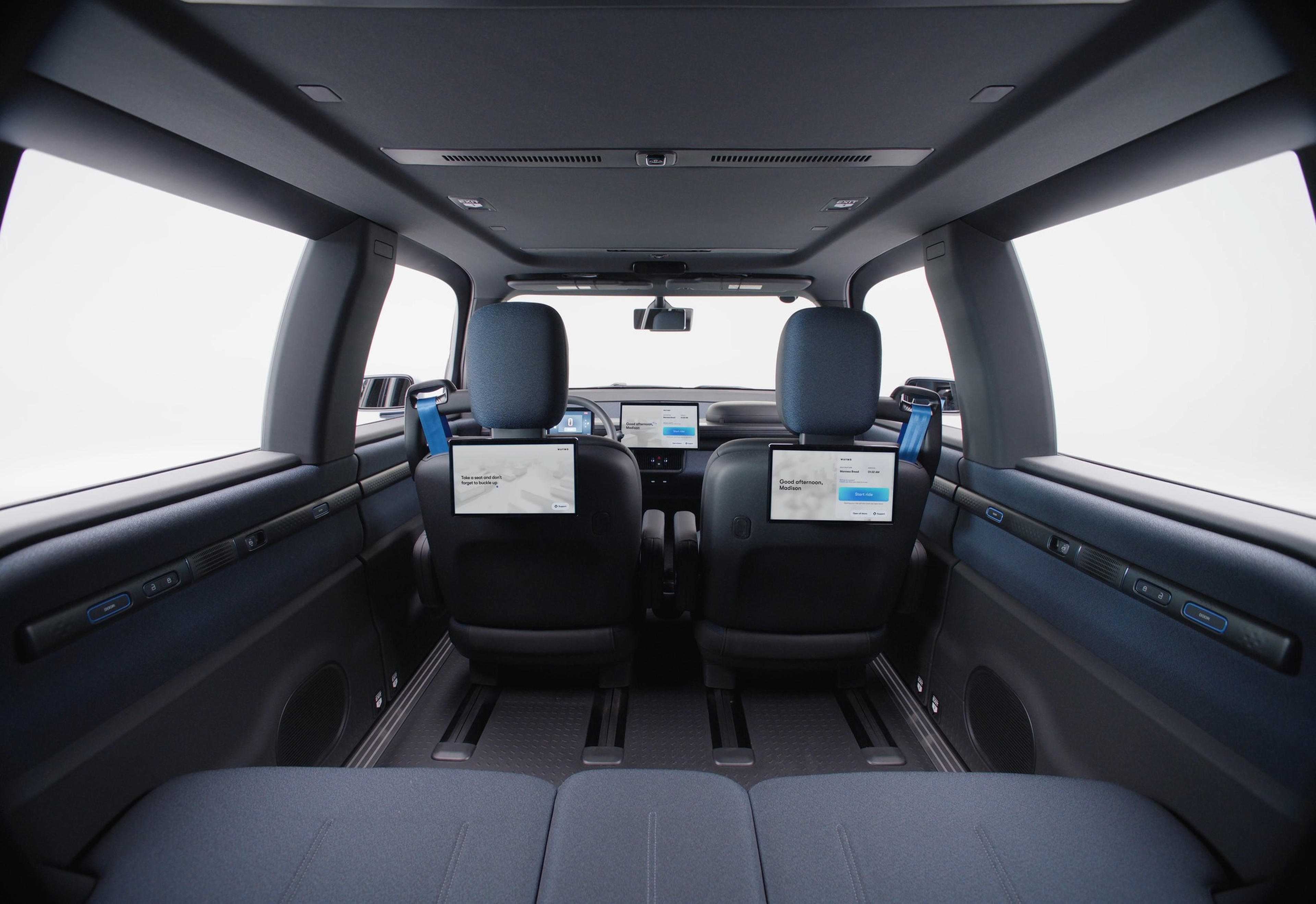 Two front car seats with screens attached to the backrests face away from the camera; a large central dashboard screen is visible.
