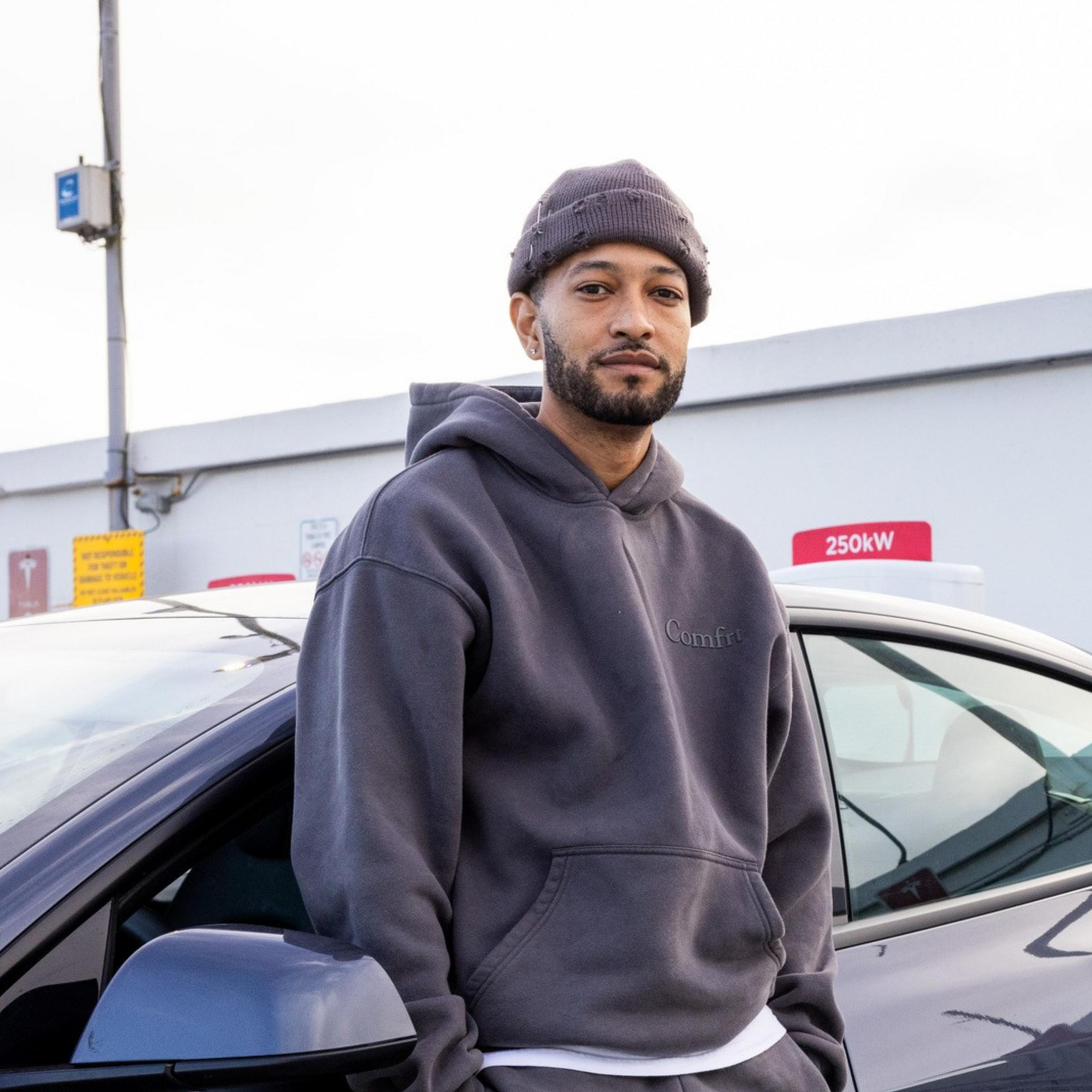 A man poses in front of his car