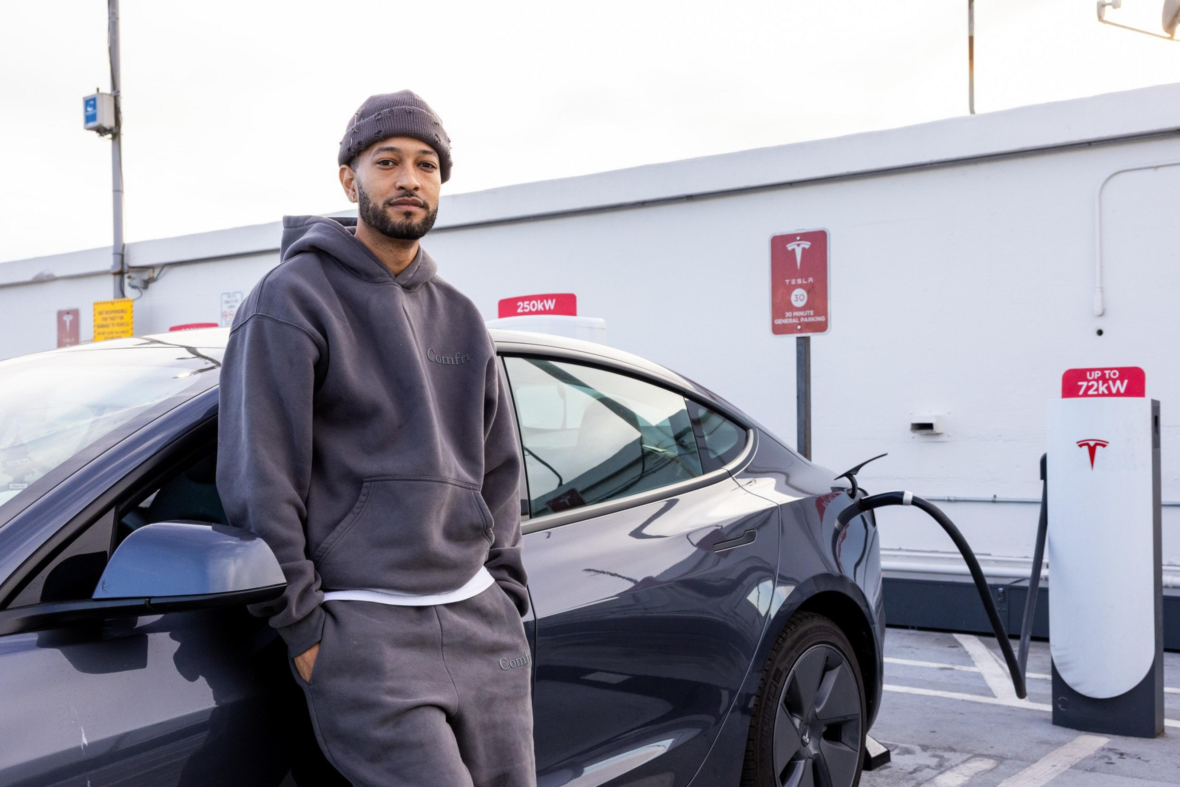 A man poses in front of his car